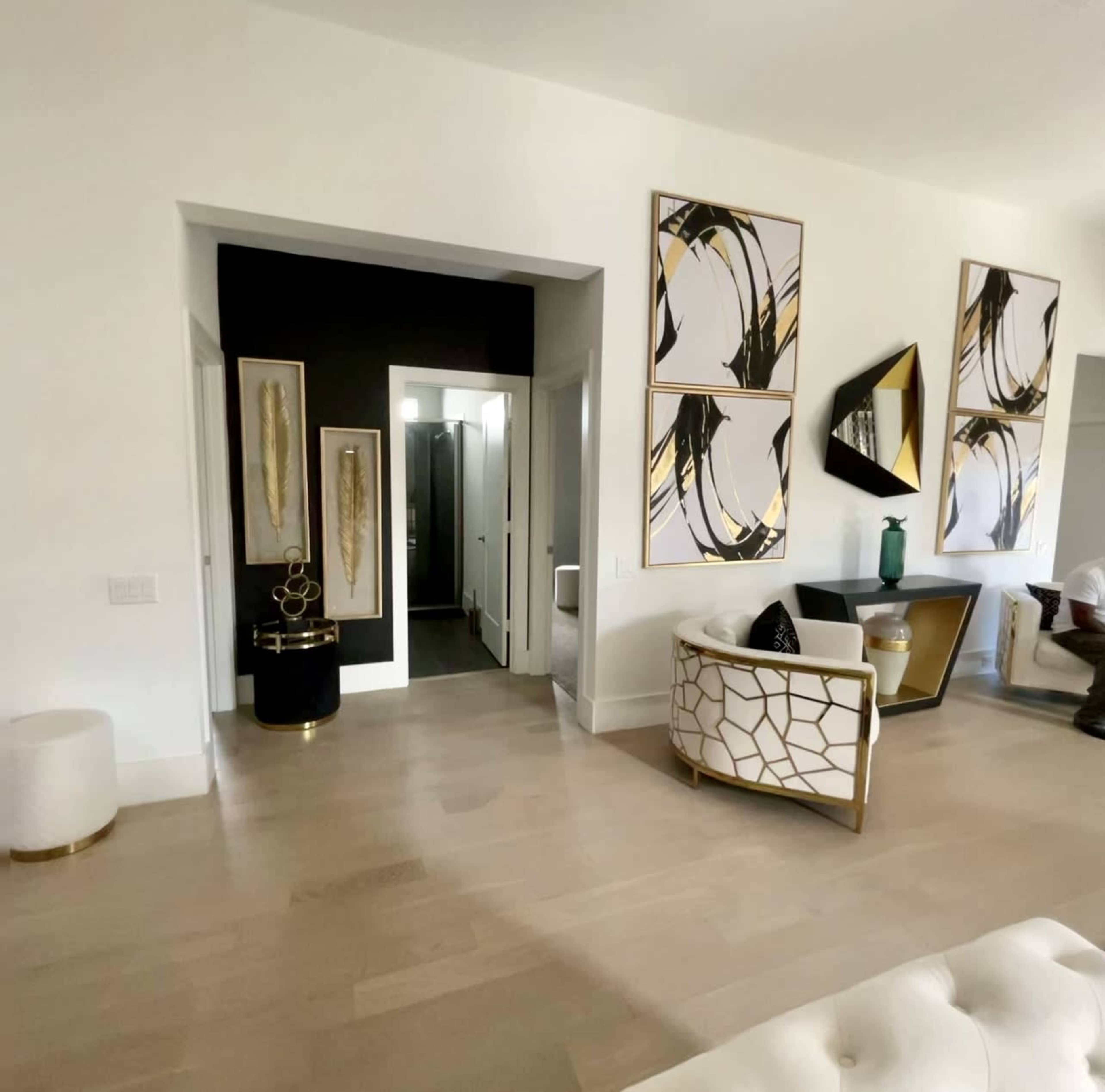 A modern interior room featuring two large abstract artworks on the wall, a chair with a geometric design, and a view of an adjoining bathroom area.
