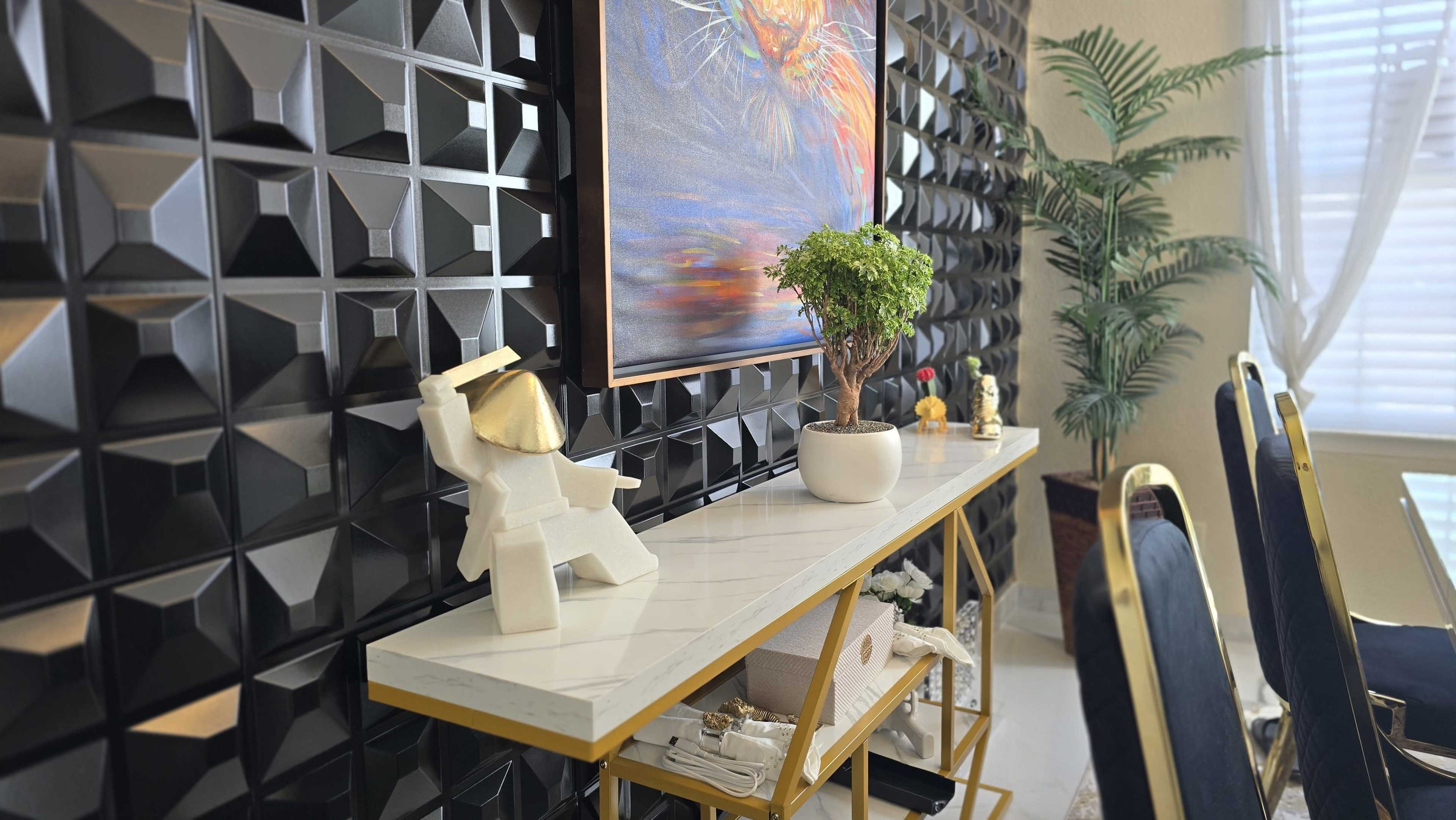 The image shows a modern interior space featuring a stylish console table with decorative items and a large artwork above it, set against a textured black wall.