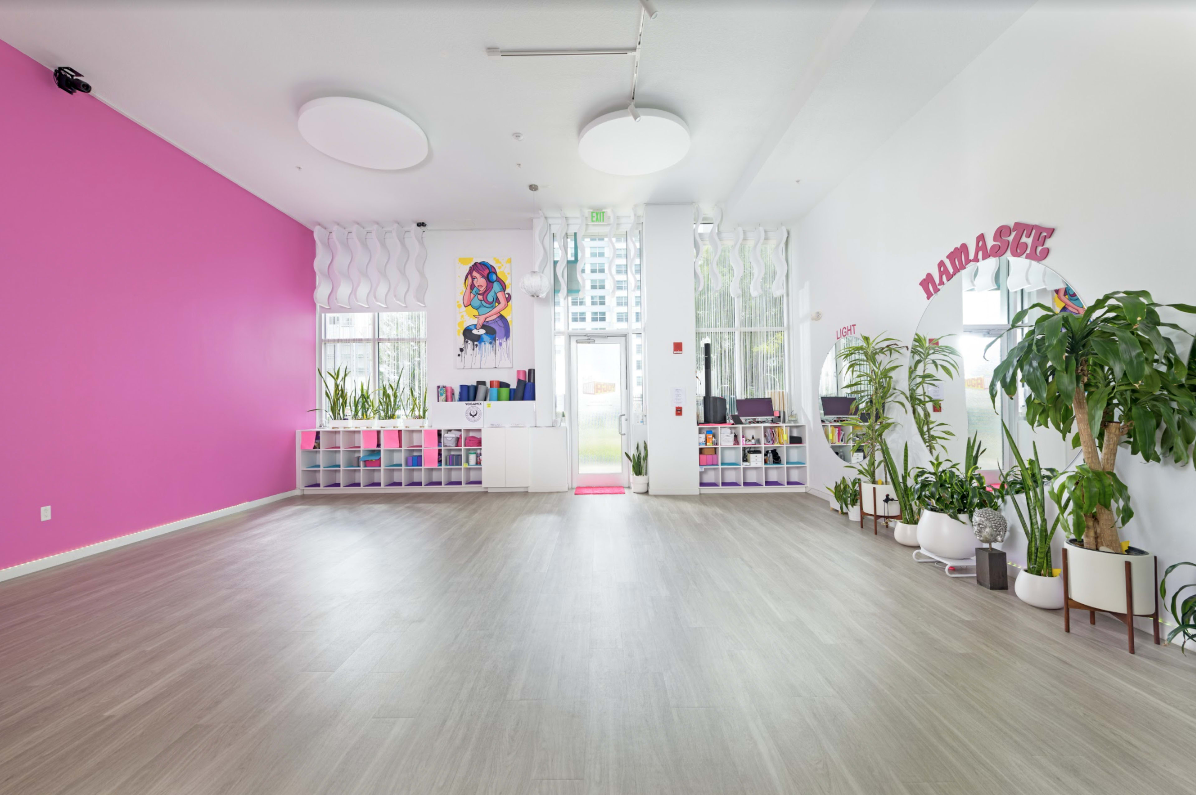 A spacious, bright room with pink walls, various plants, and an entryway featuring the word "Namaste."