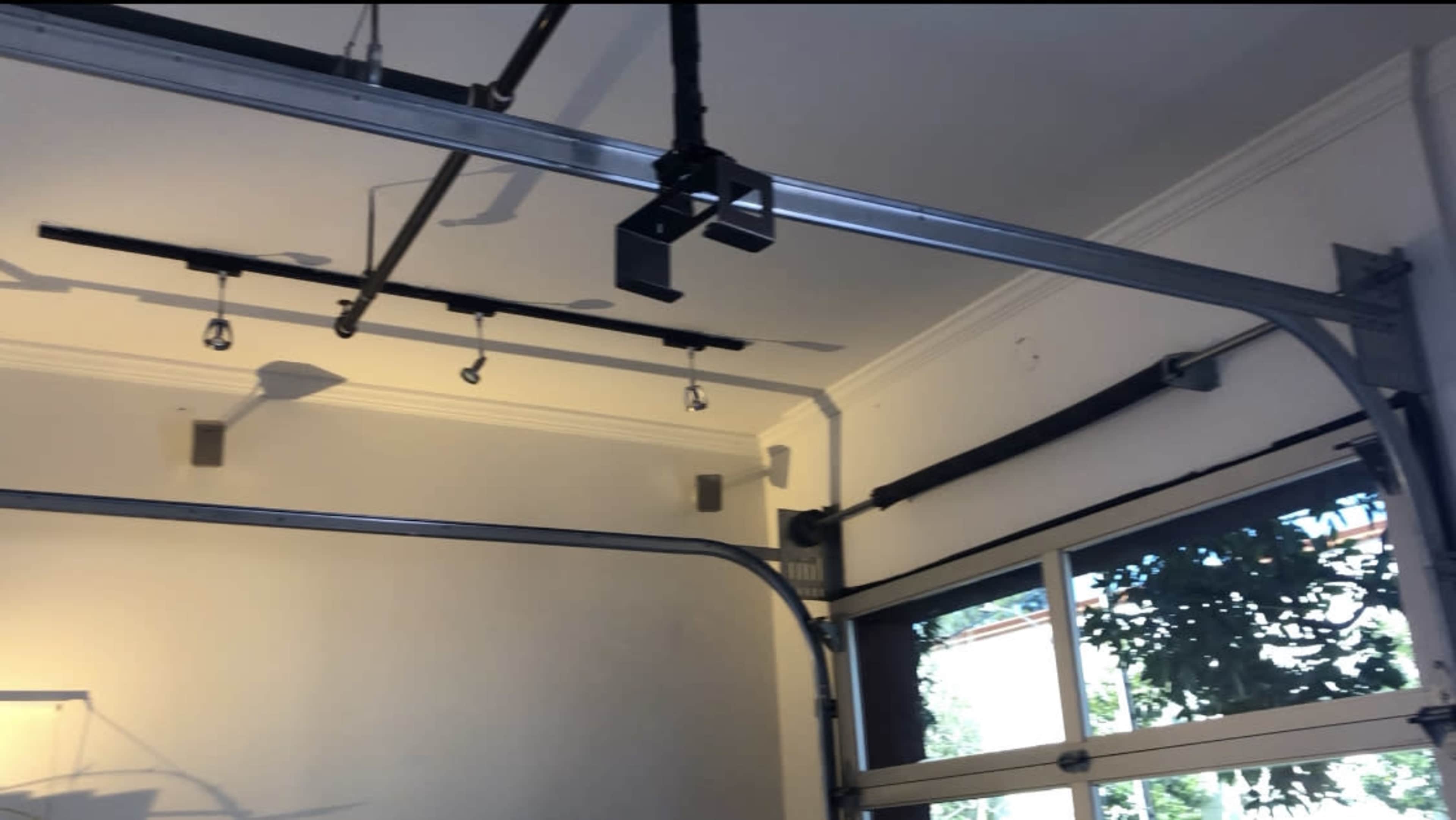 A ceiling-mounted track system with metal components and a large window allowing light into the room.