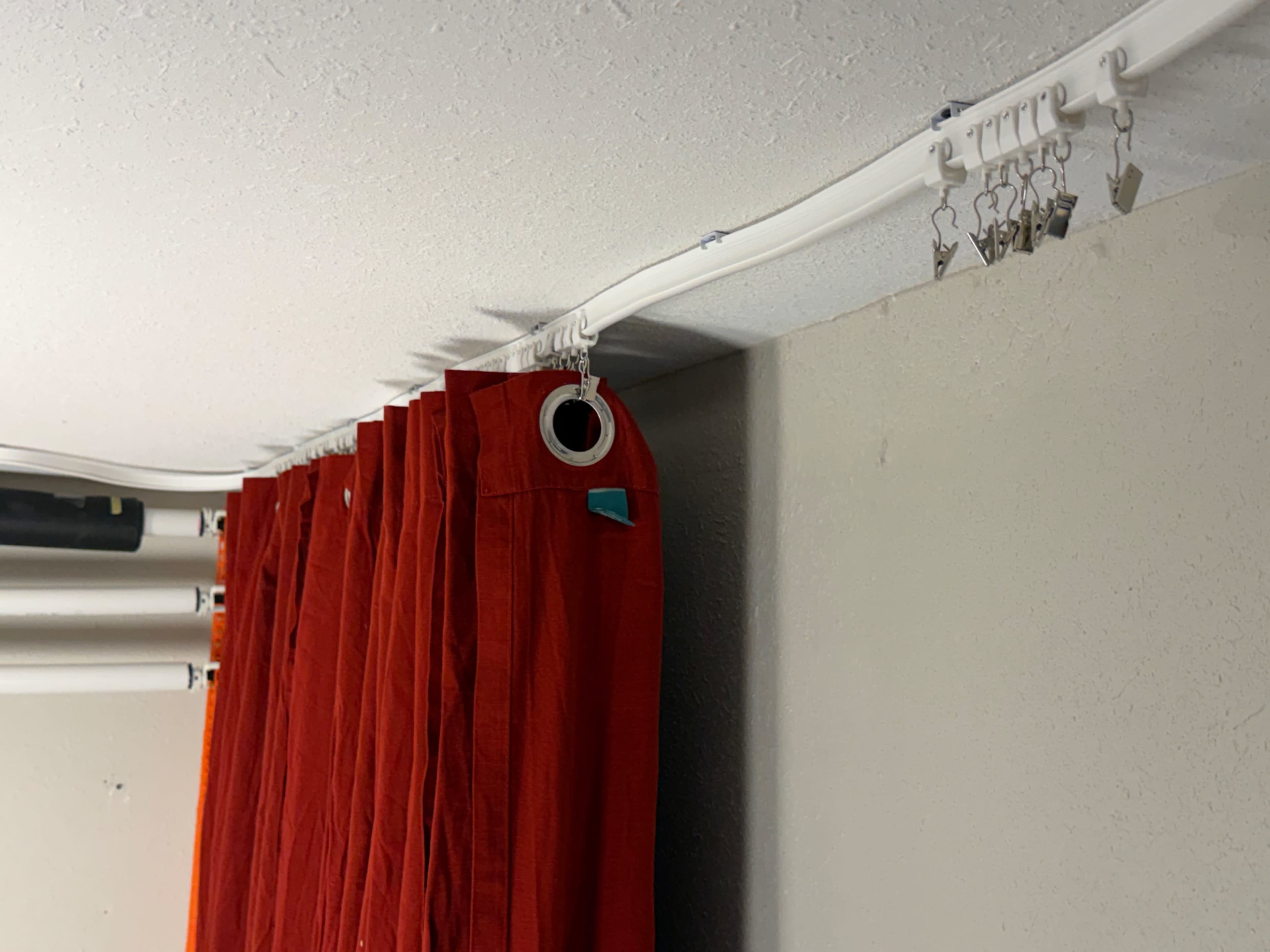 The image shows a section of red curtains hanging from a white track mounted to a ceiling.