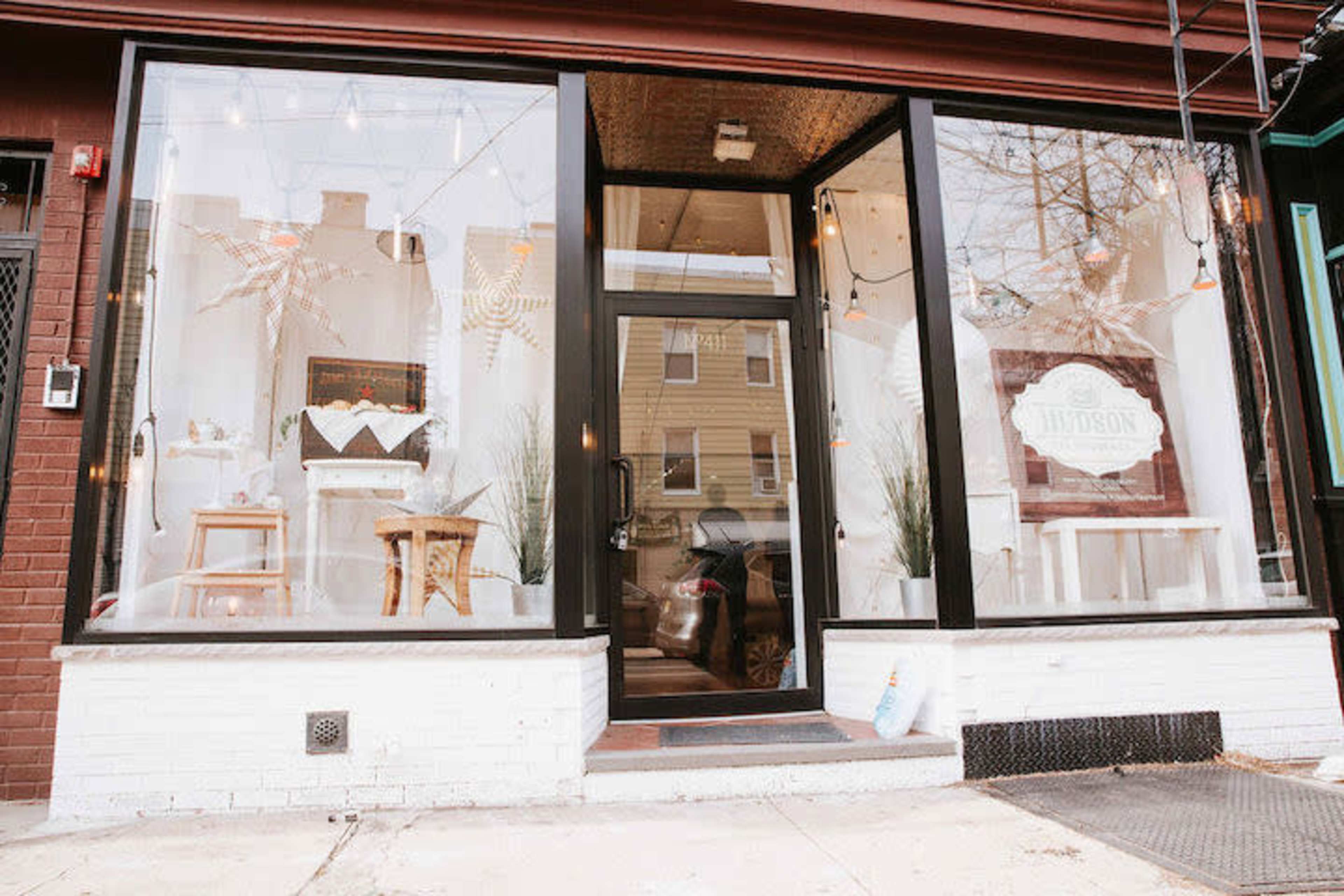 A storefront with large glass windows, featuring minimalist interior decor and a sign that reads "Hiverson."