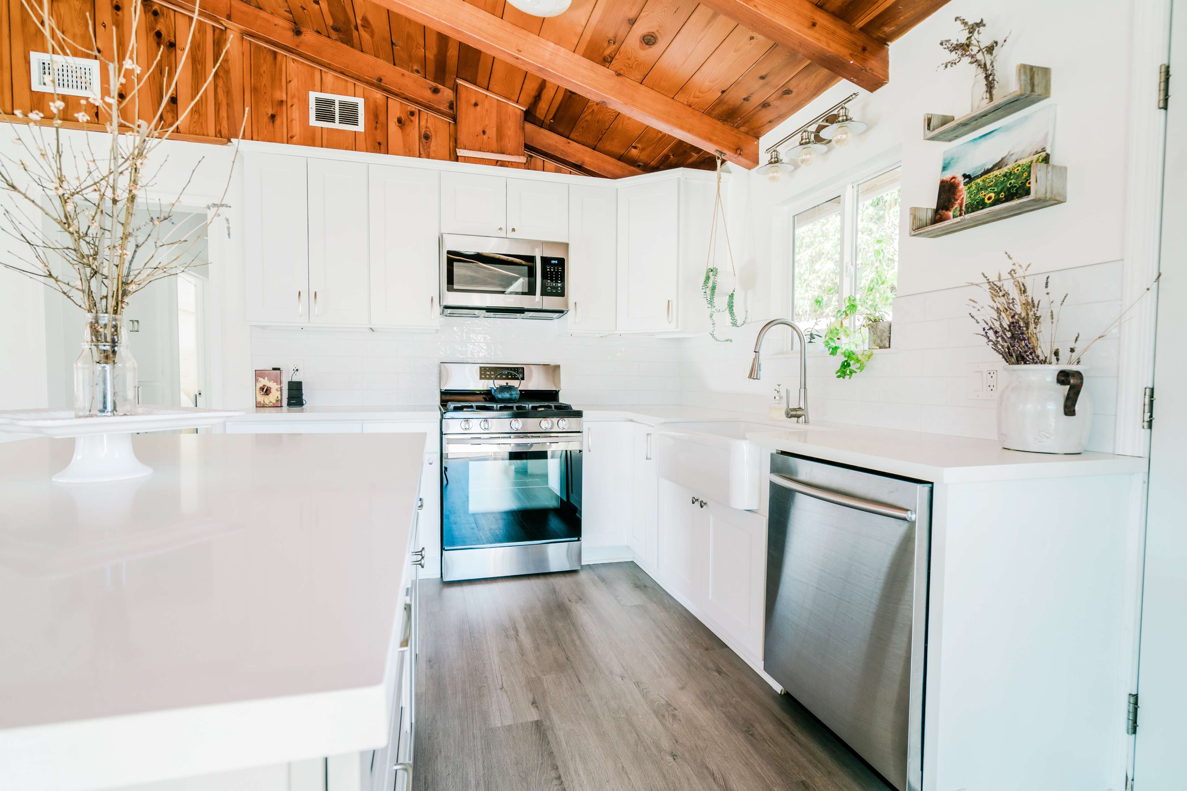 The kitchen features white cabinets, stainless steel appliances, and a wooden ceiling with exposed beams.