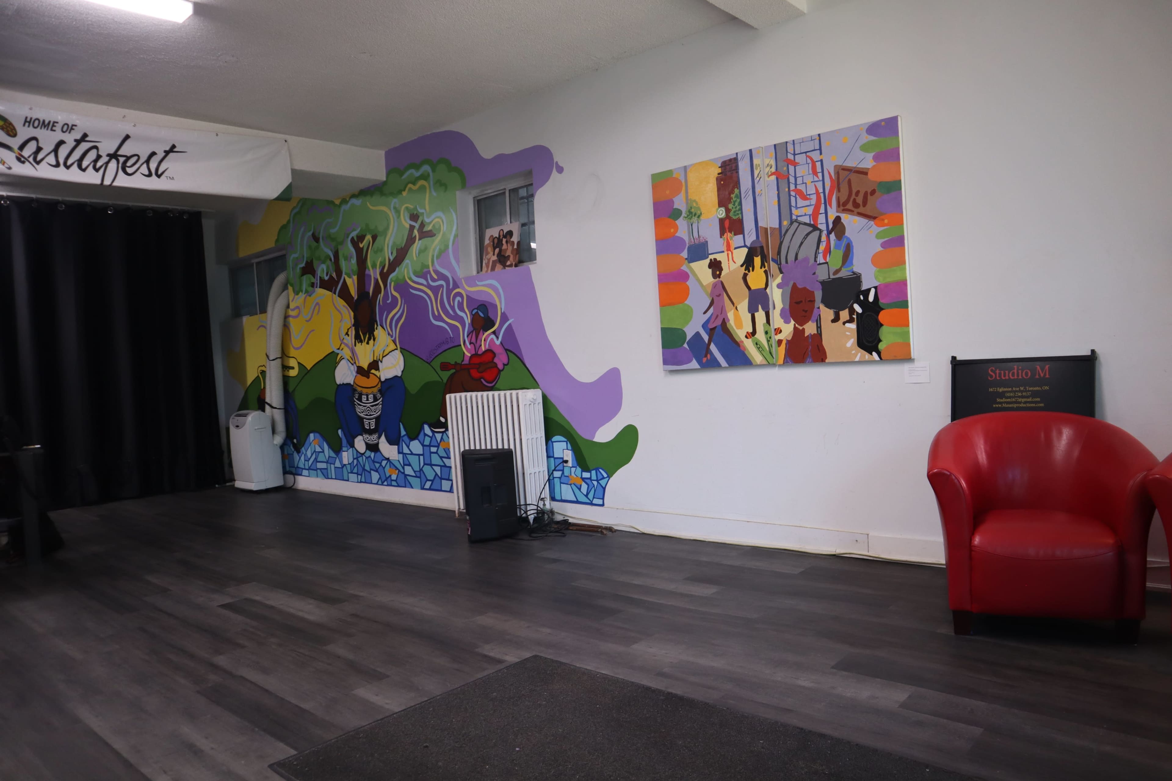 The image shows a room with a colorful mural on one wall and a red armchair in the corner, alongside a black speaker and a sign for "Studio M."