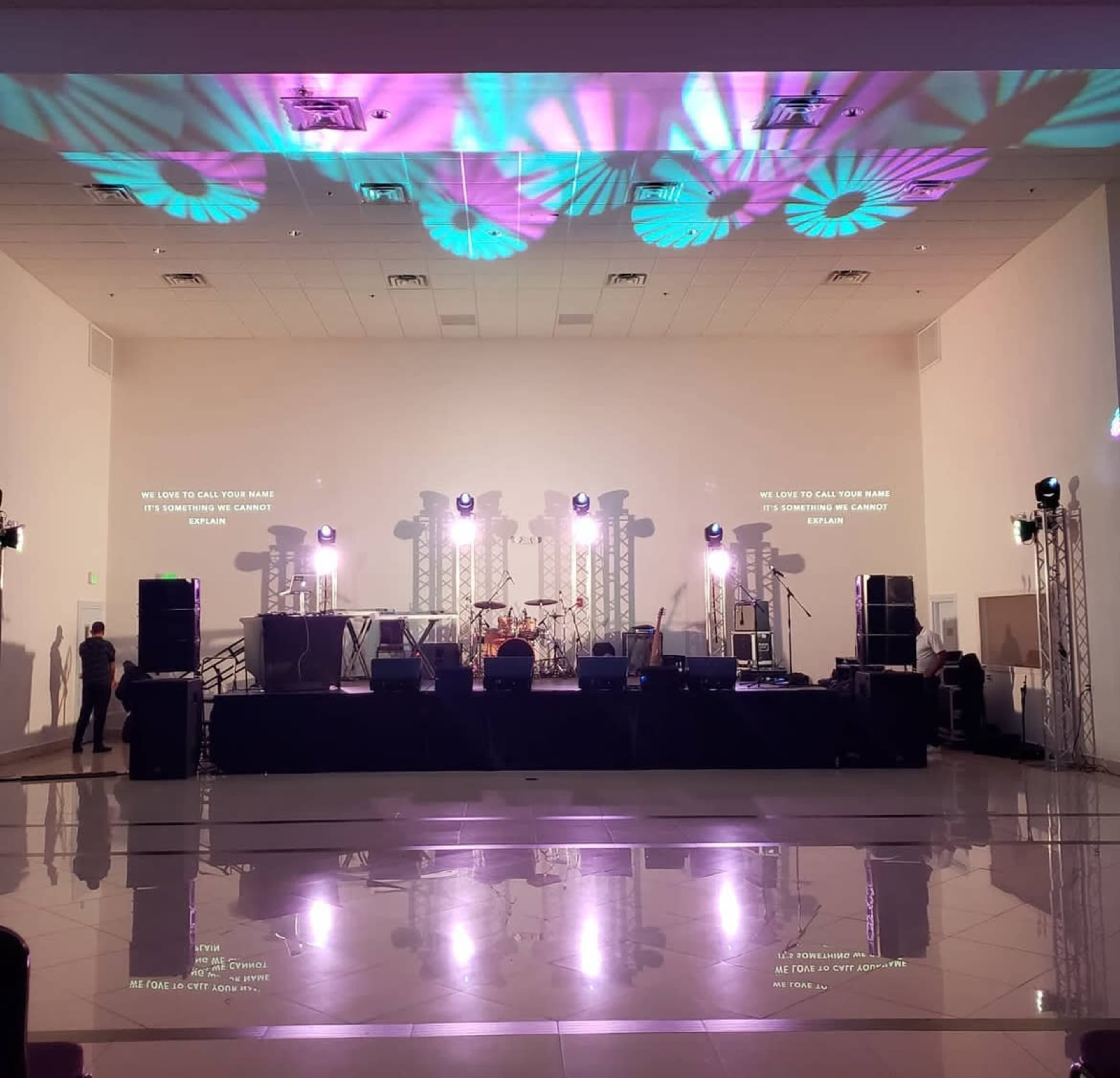 A stage is set up with lighting and sound equipment in a large, well-lit venue, ready for a performance.