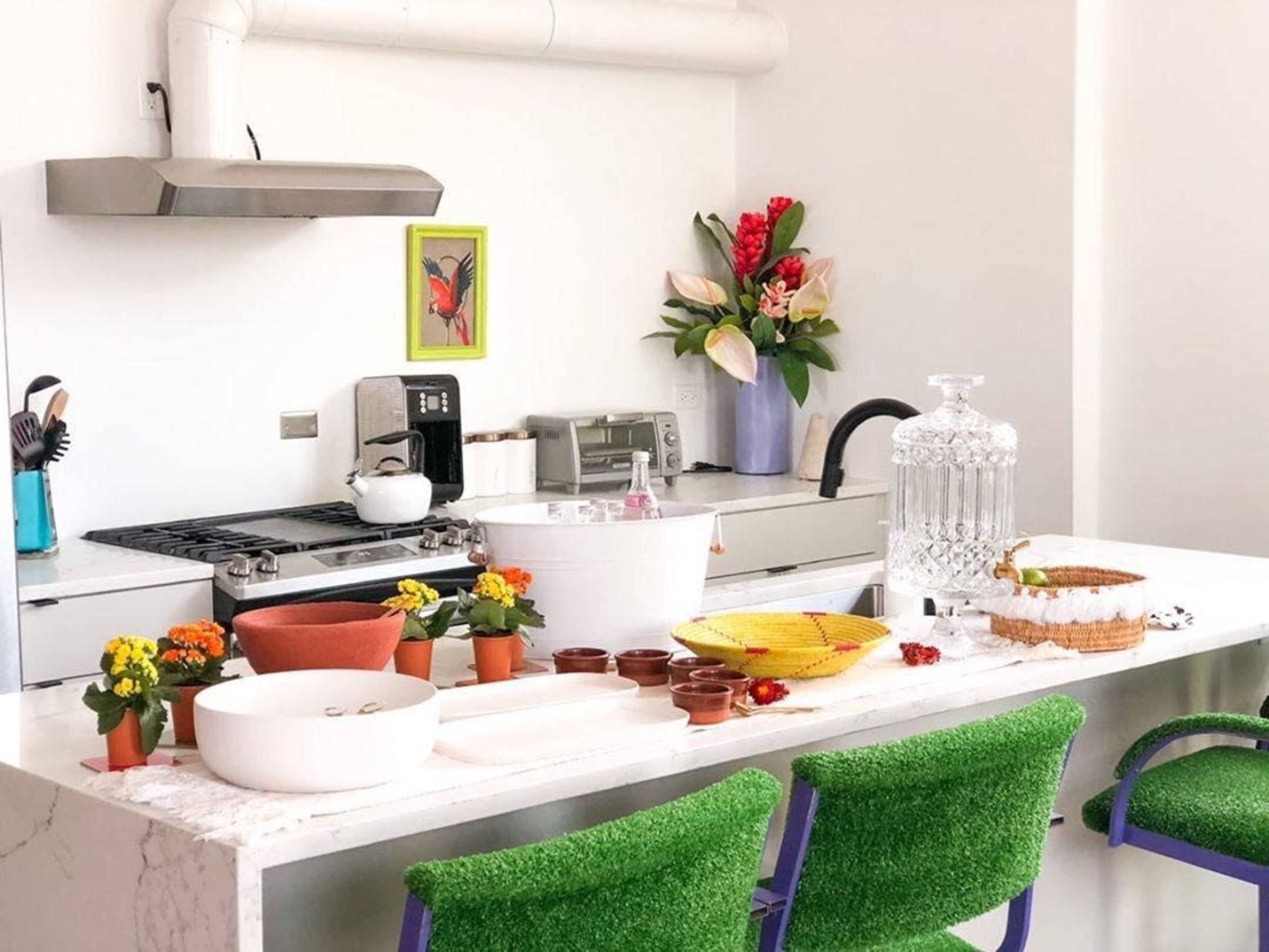 A modern kitchen features a marble countertop with potted plants, kitchen appliances, and decorative items arranged neatly.