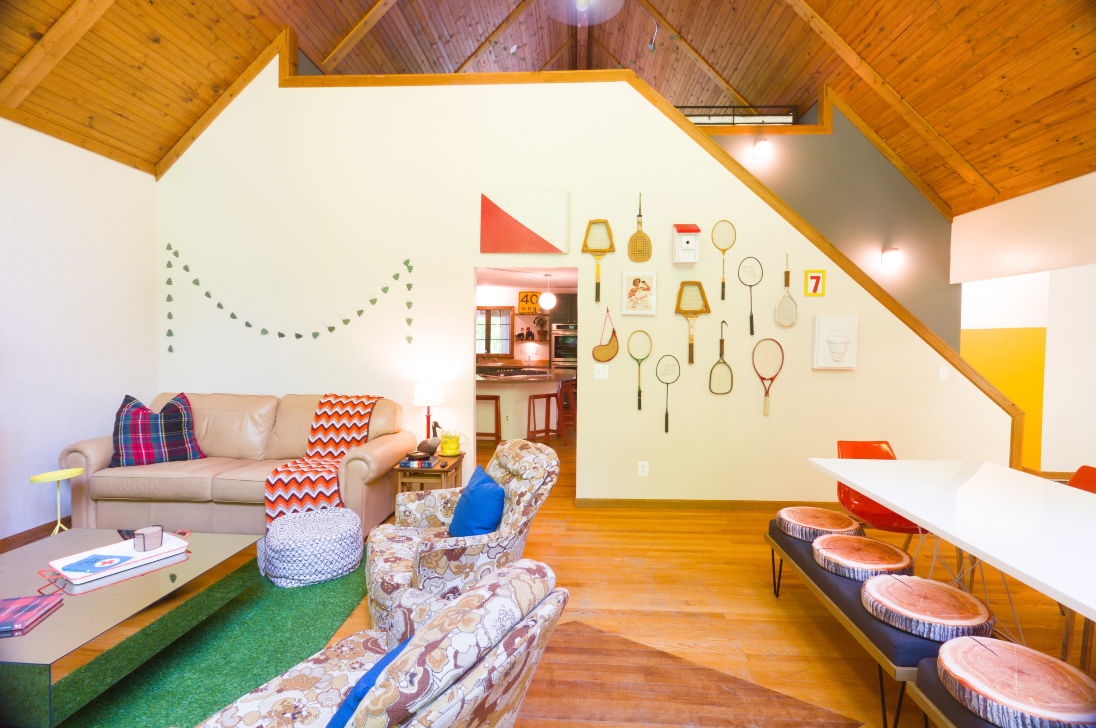 The image shows a cozy living space with a mix of modern and vintage furniture, featuring wooden ceilings and walls adorned with decorative items.