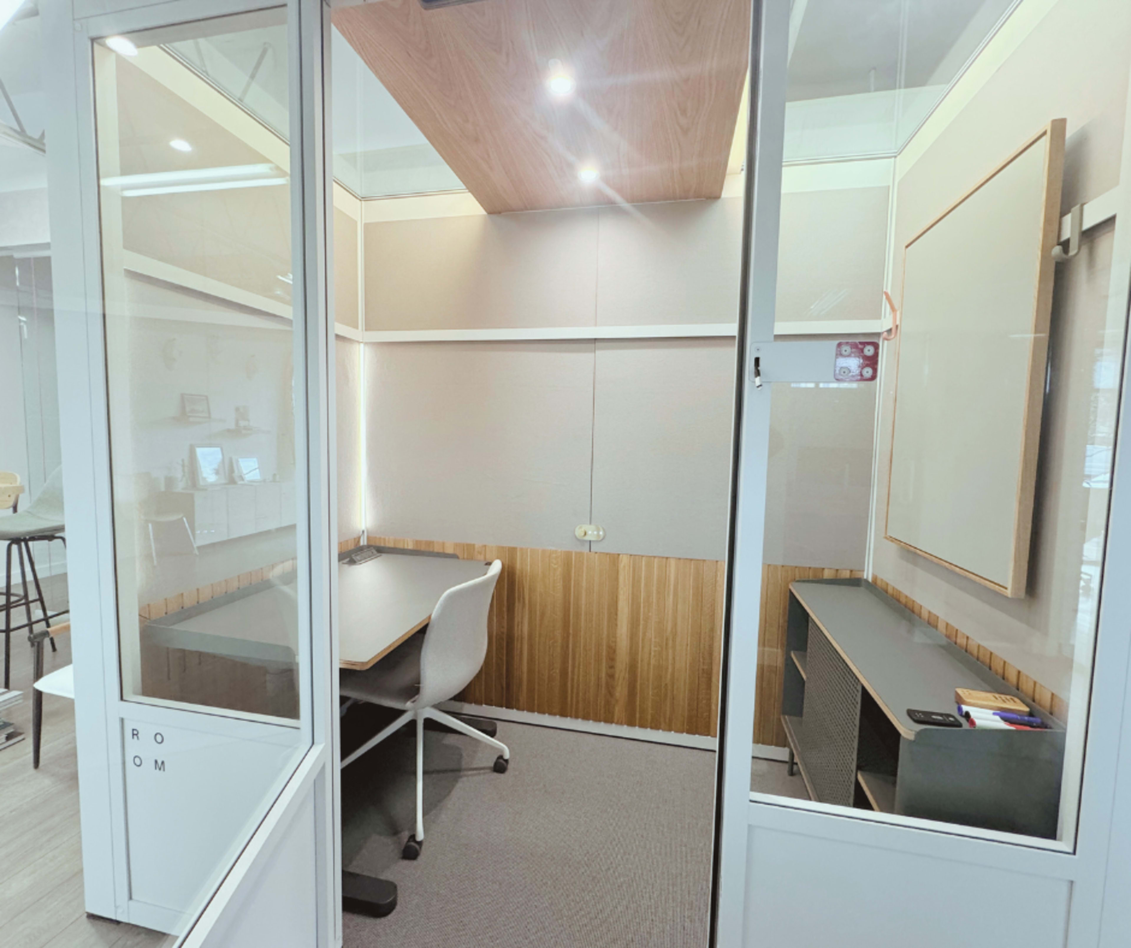 The image shows a modern, enclosed study room with a desk, chair, and a whiteboard on the wall.