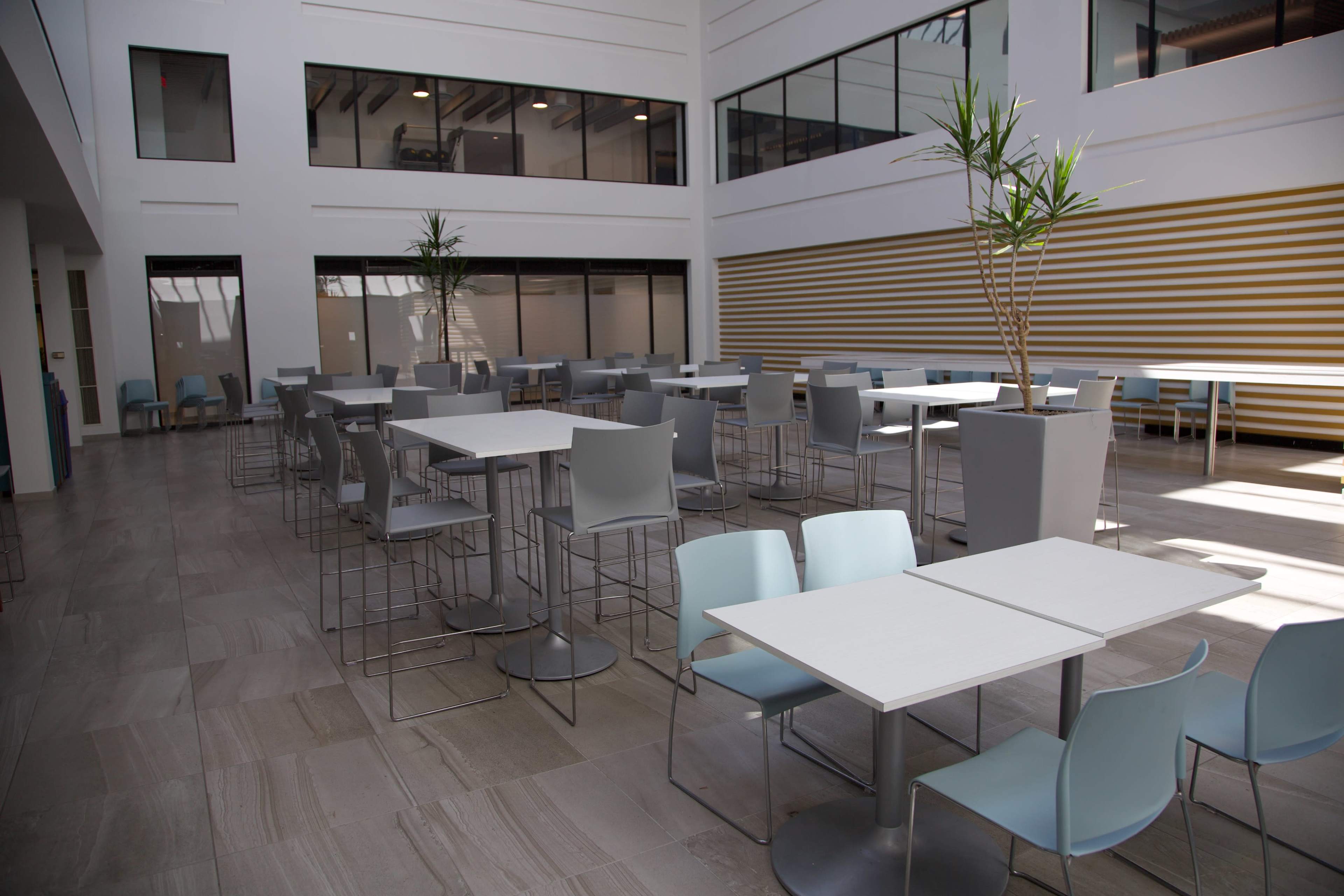 The image shows a spacious indoor seating area with tables and chairs arranged in a modern design.