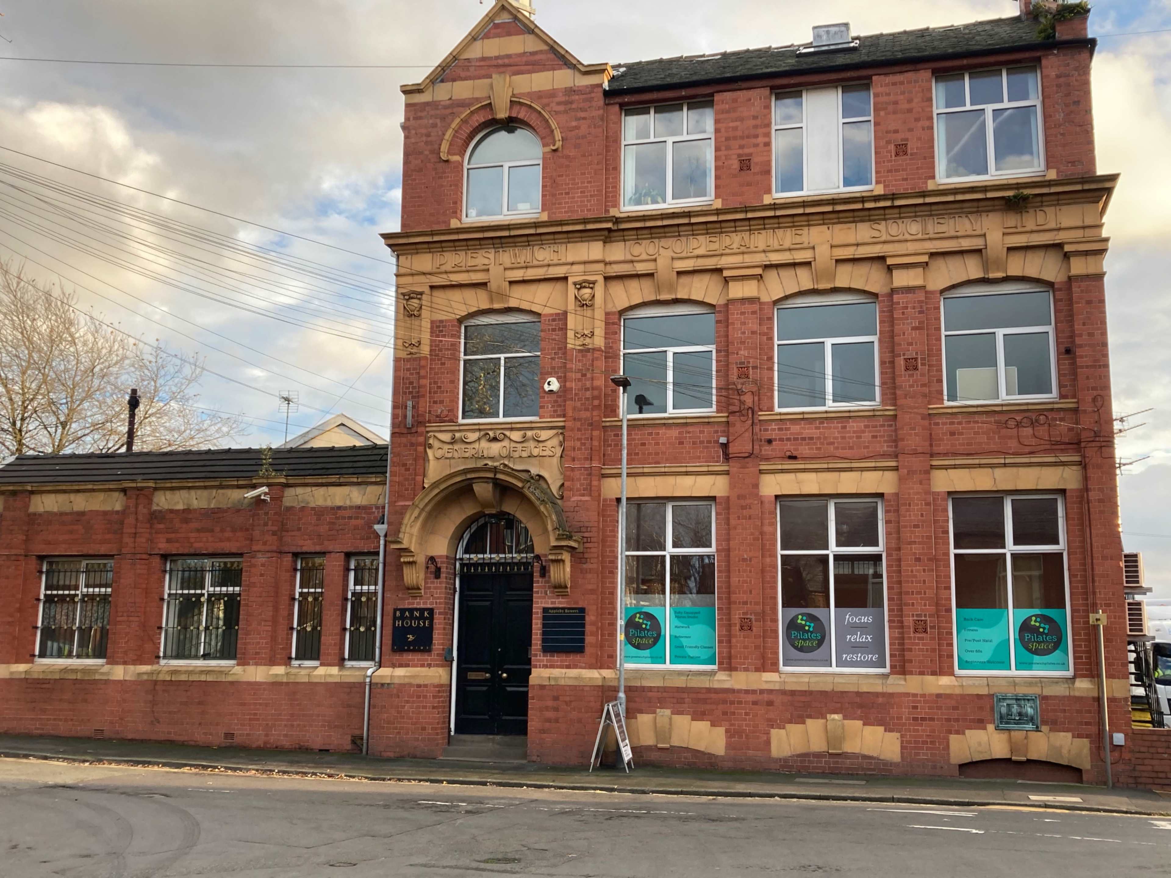 A red brick building with ornate architectural details, featuring large windows and a decorative entrance labeled "Cooperative Society."