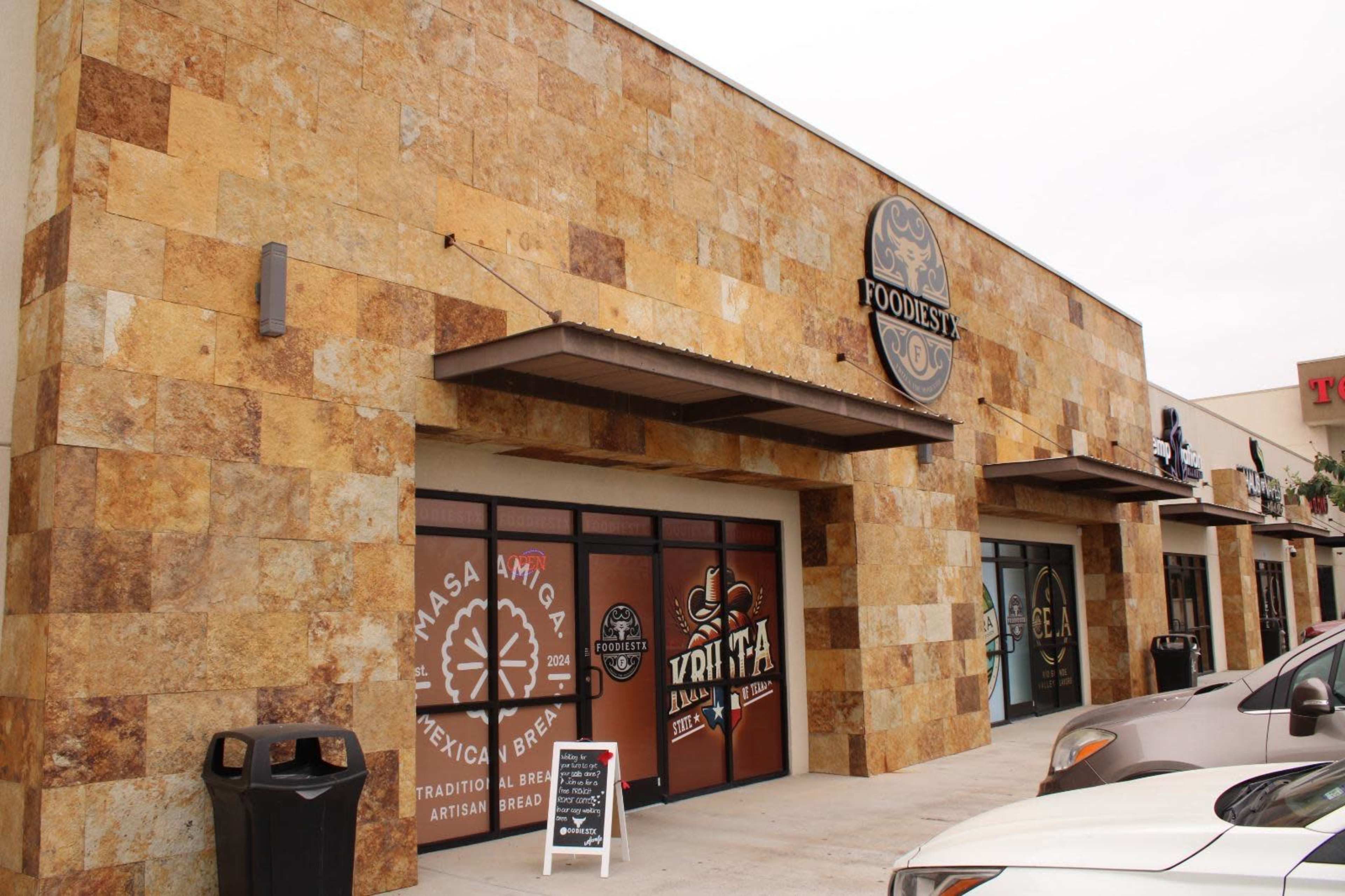 The image shows a textured stone facade of a building with multiple storefronts, including one marked "Masa Amiga" and another labeled "Yrita."