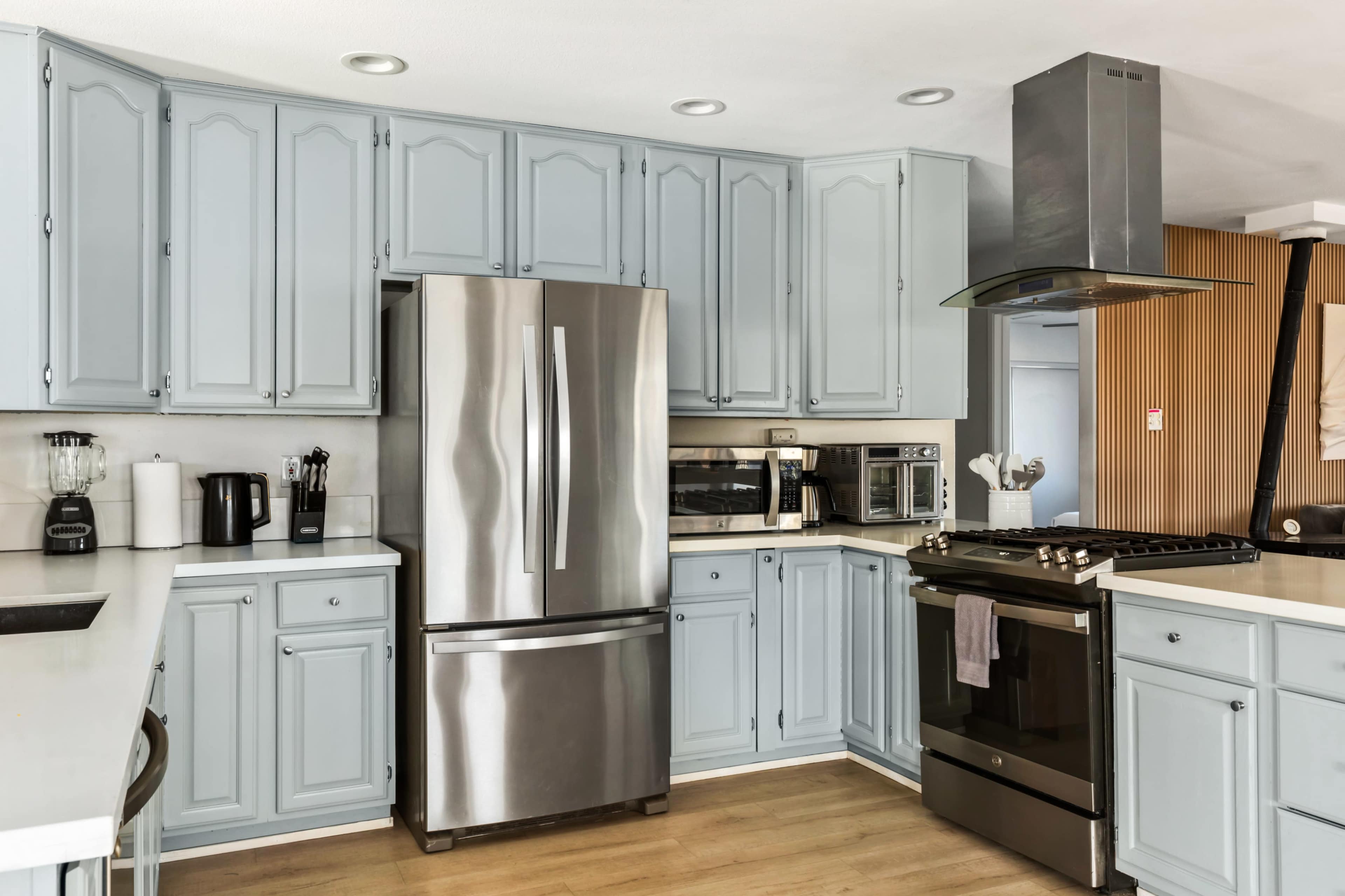 The kitchen features light blue cabinetry, stainless steel appliances, and a modern gas stove.