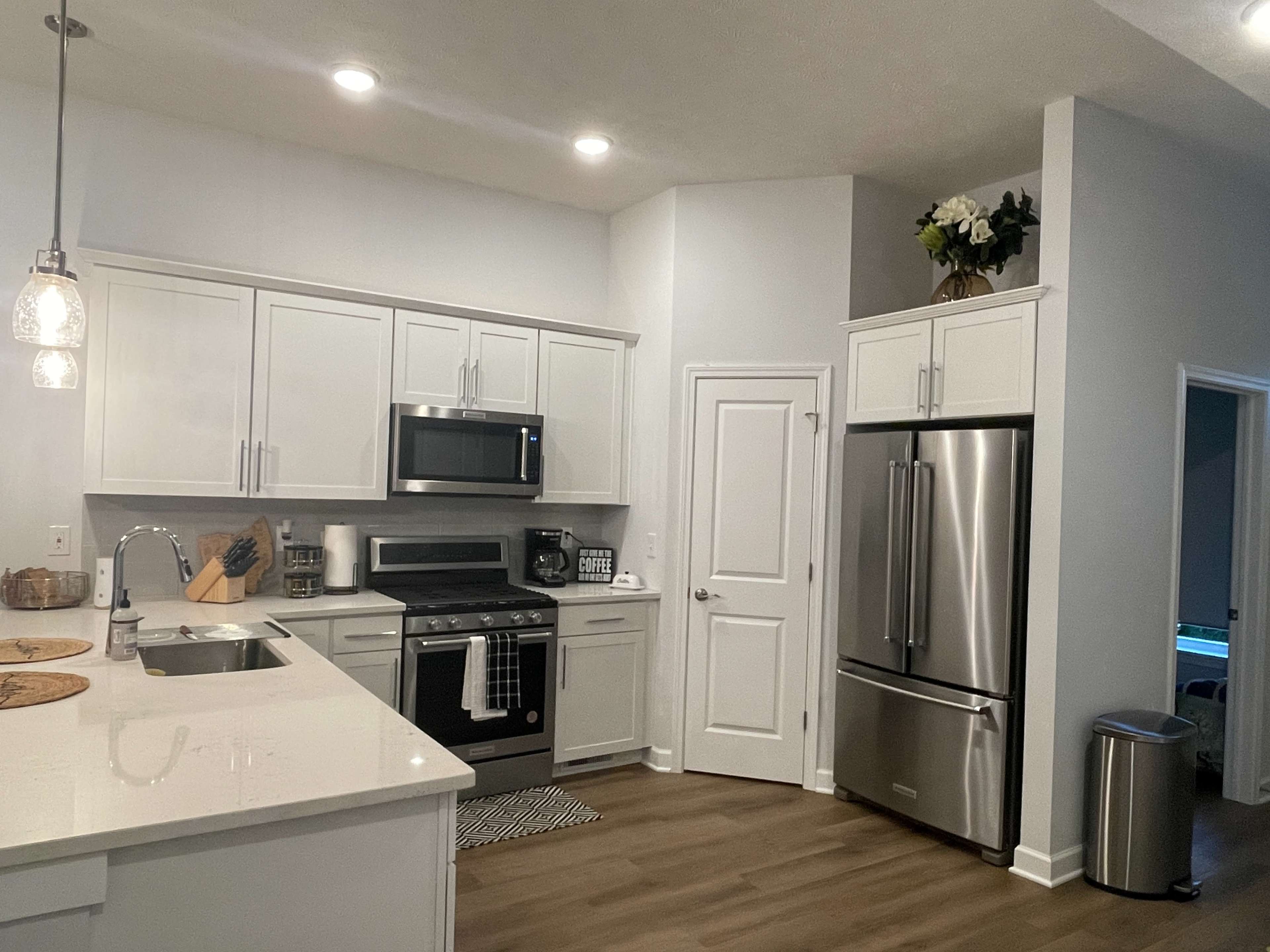A modern kitchen with white cabinets, stainless steel appliances, and a spacious layout featuring an island with a sink.