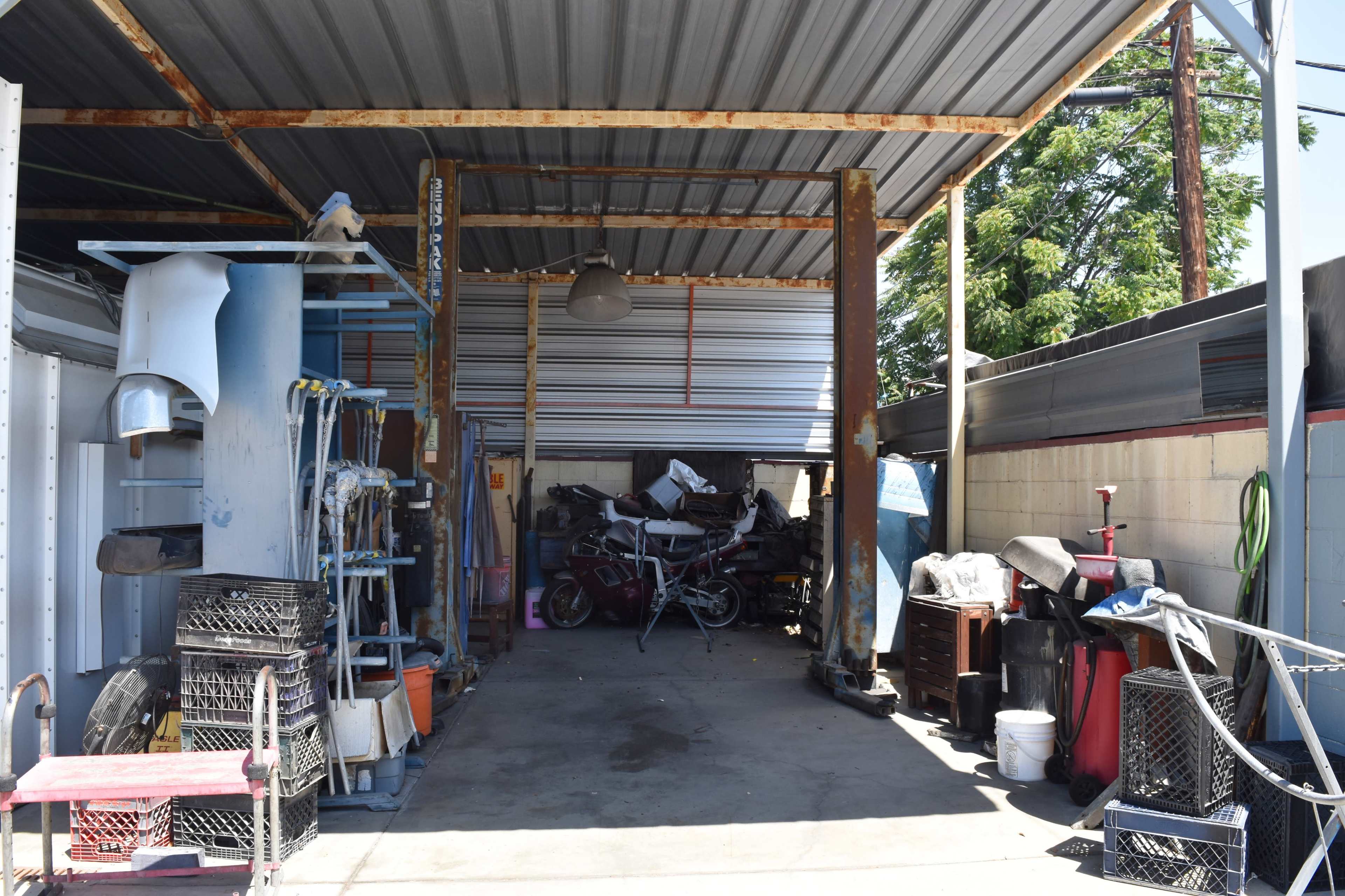 The image shows a cluttered garage or workshop with various tools, equipment, and a motorcycle partially obscured in the background.