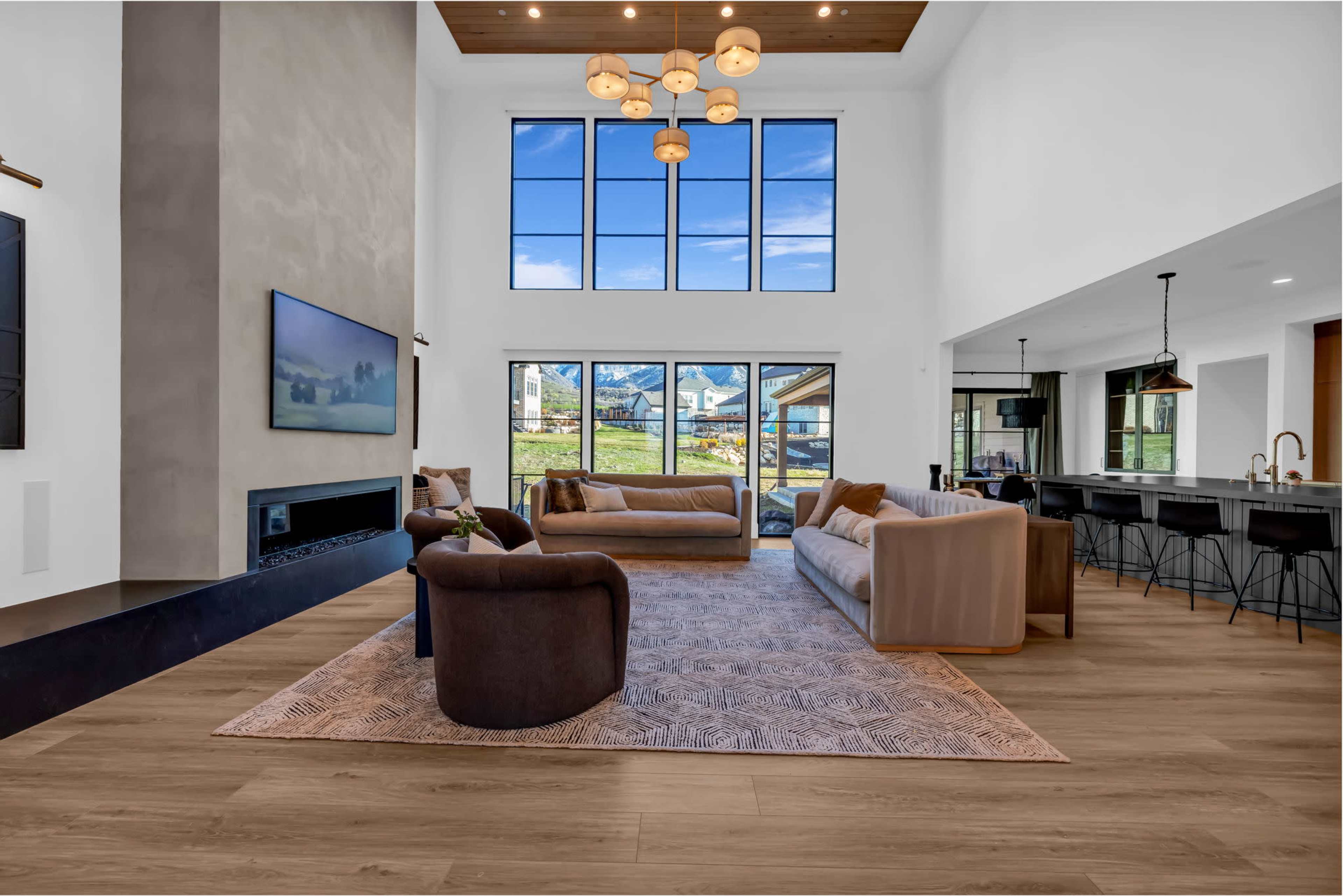 The room features a spacious living area with large windows, a contemporary fireplace, and a modern kitchen in the background.