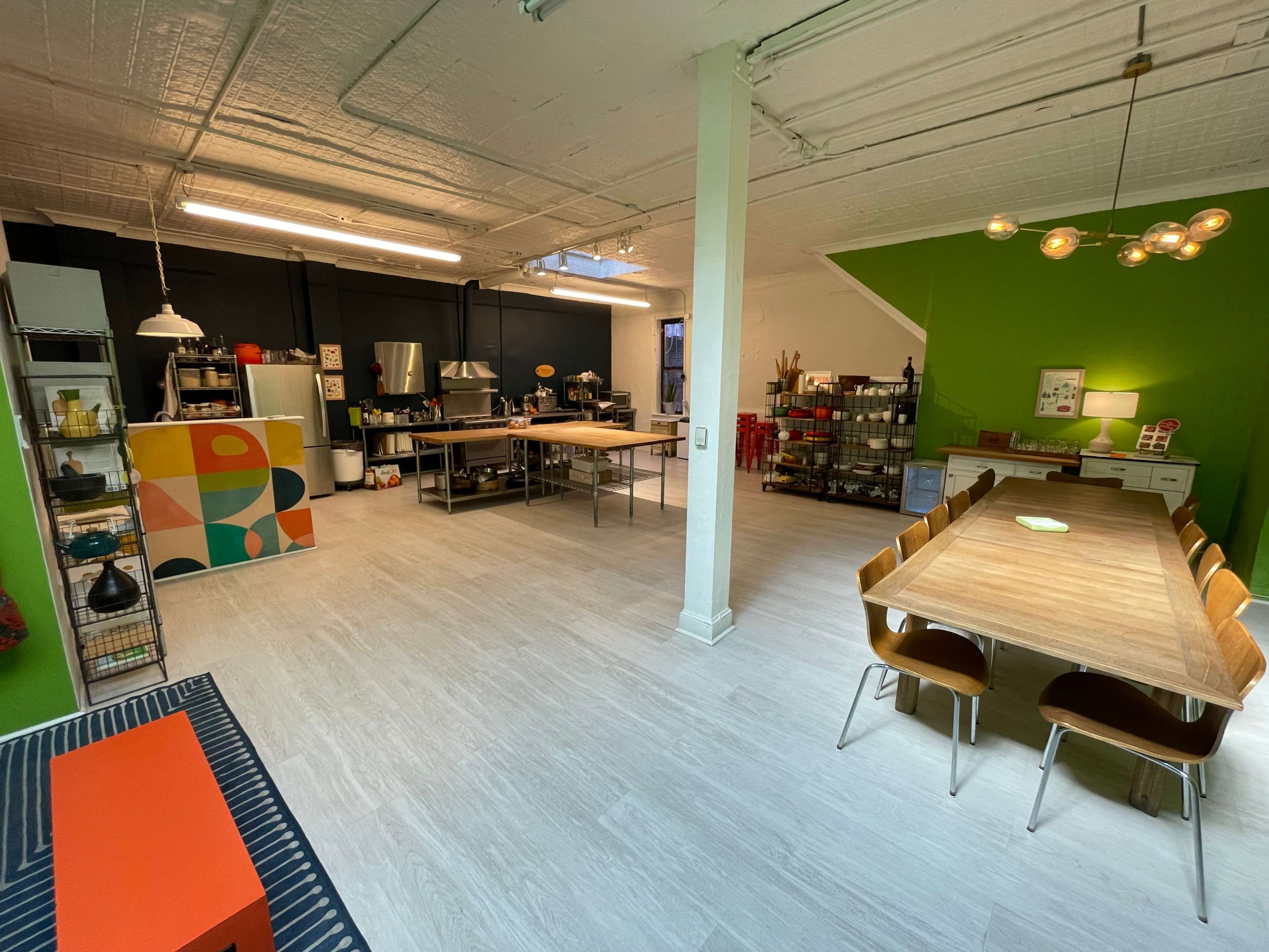 A spacious kitchen and dining area with modern appliances, a large wooden table, and vibrant green walls.