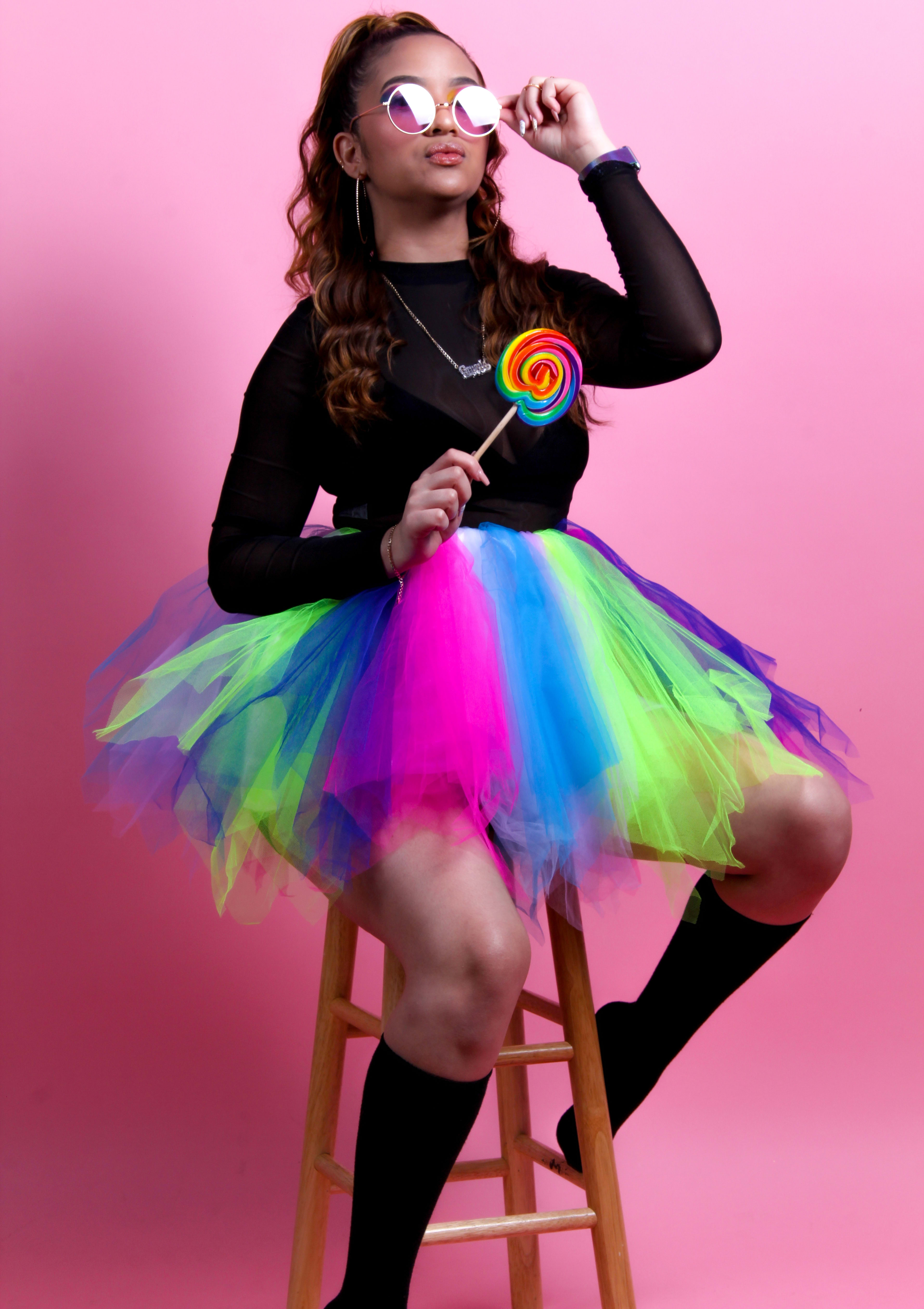 A fashion photo shoot featuring a woman holding a rainbow lollipop.