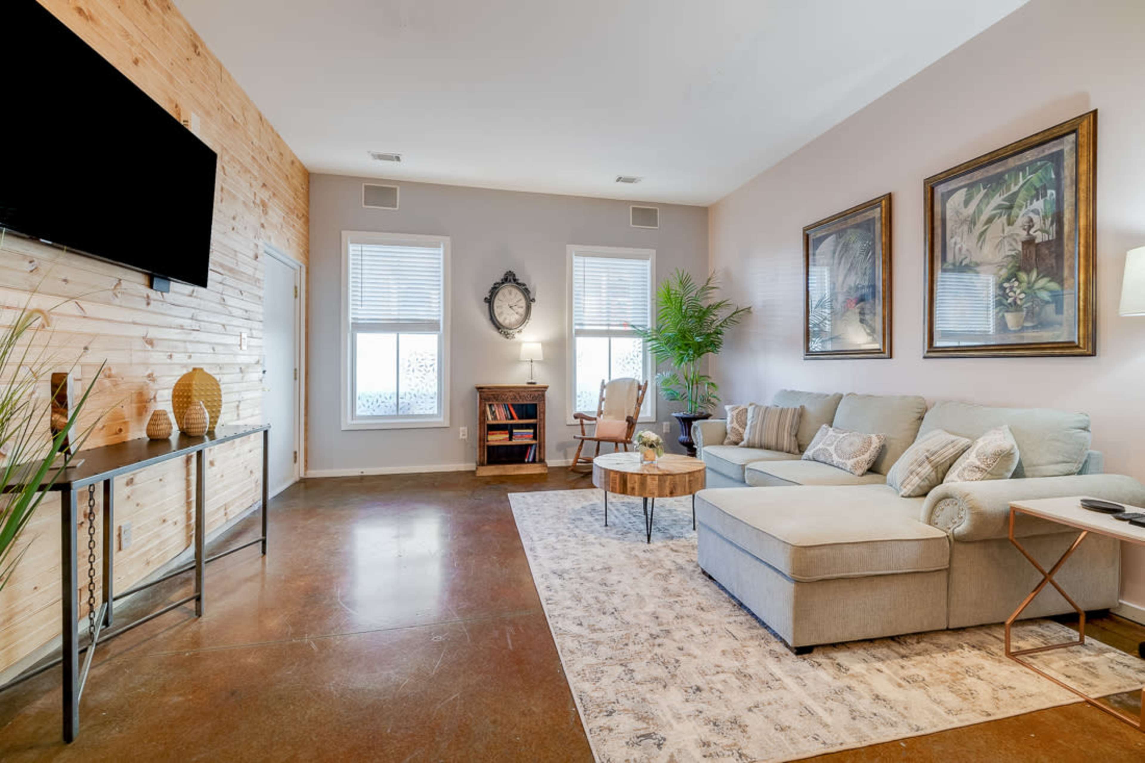A modern living room featuring a sectional sofa, a wooden accent wall, a round coffee table, and various decorative elements.