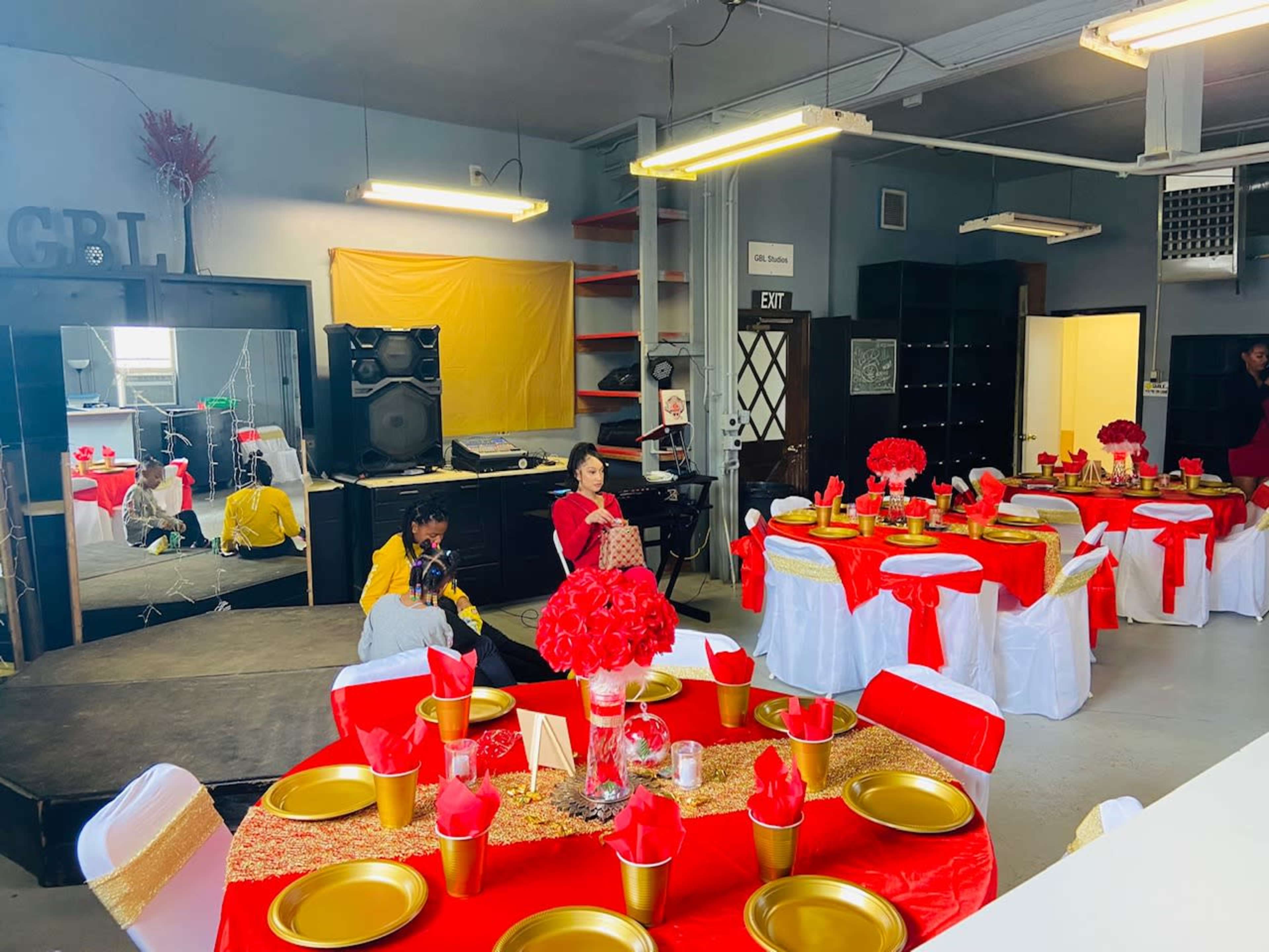 The scene depicts a banquet hall set up for an event, featuring tables adorned with red and gold decorations, and chairs draped in white and red fabric.