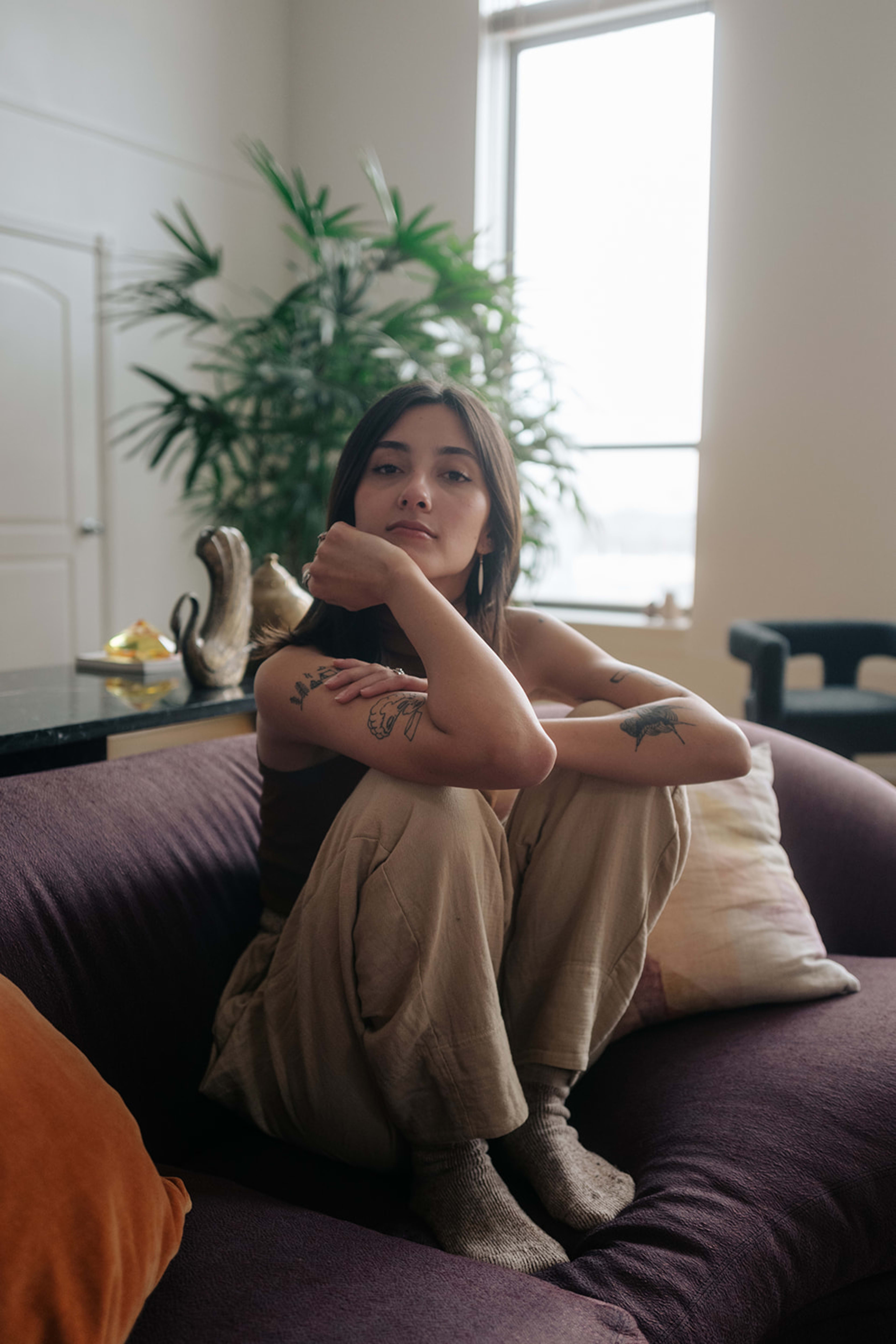 A woman posing on a purple couch during a photoshoot.