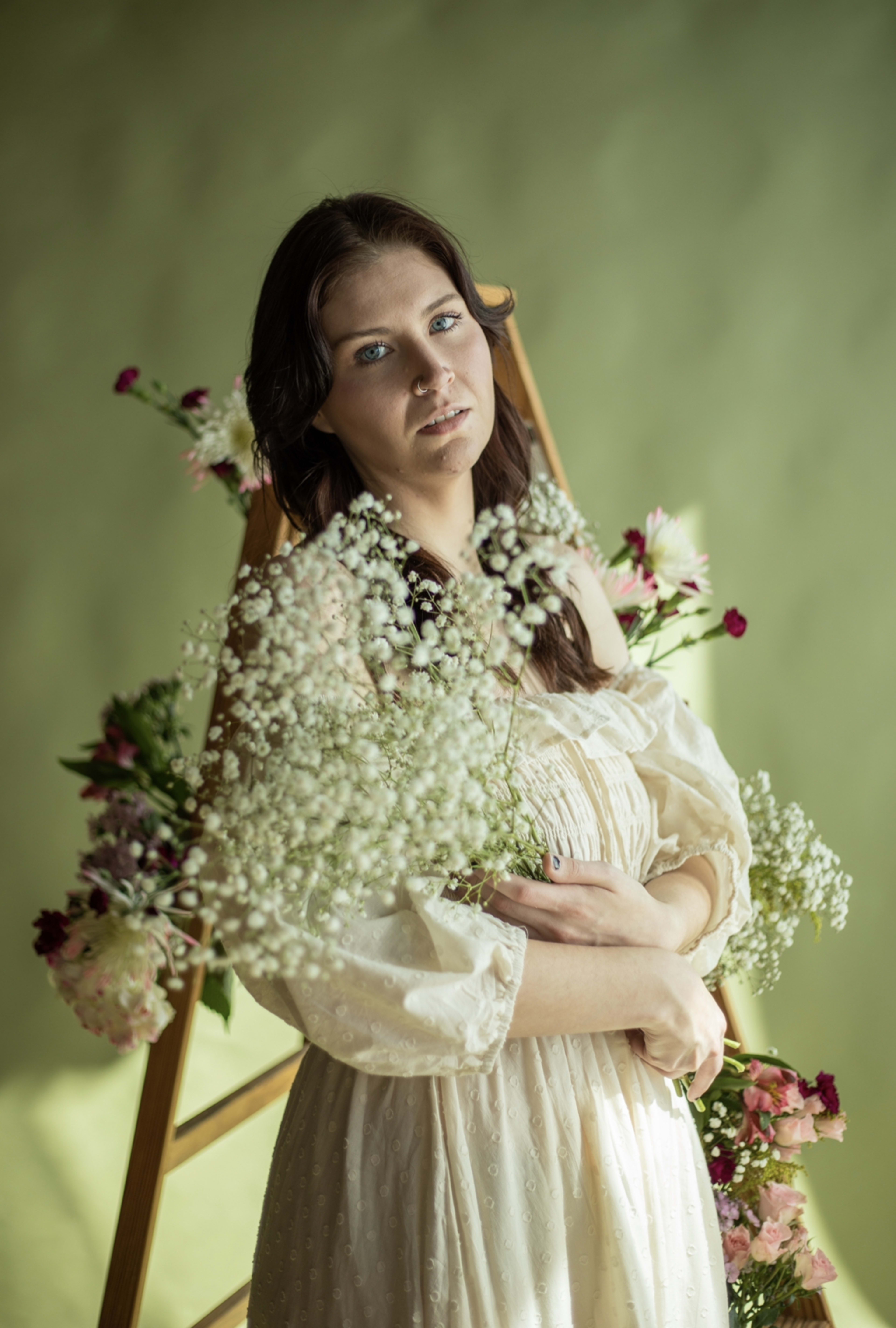 A fashion photoshoot featuring a white-dressed woman and a bouquet of spring flowers.