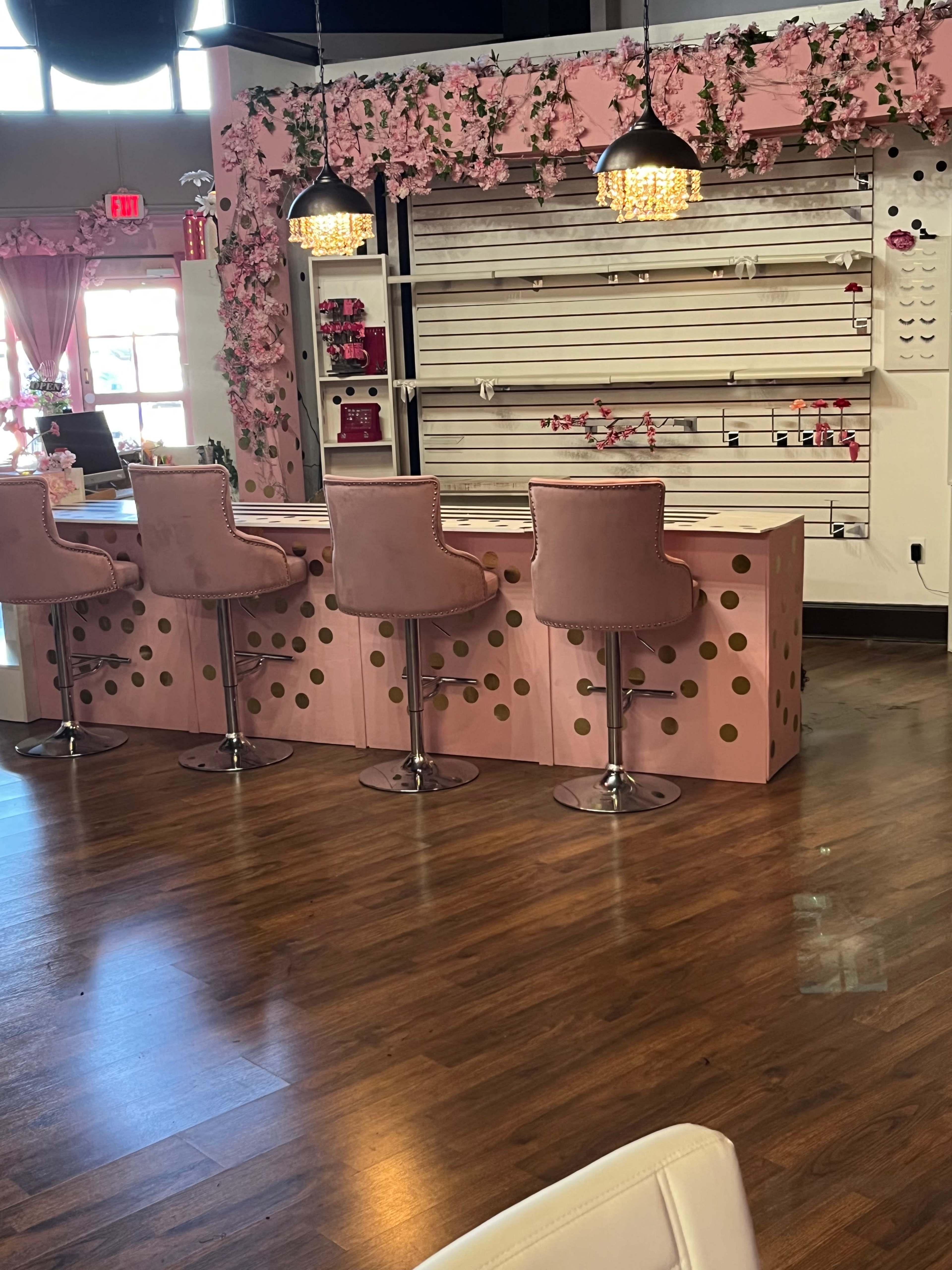 A pink and white interior space with a countertop featuring round gold polka dots and four pink bar stools.