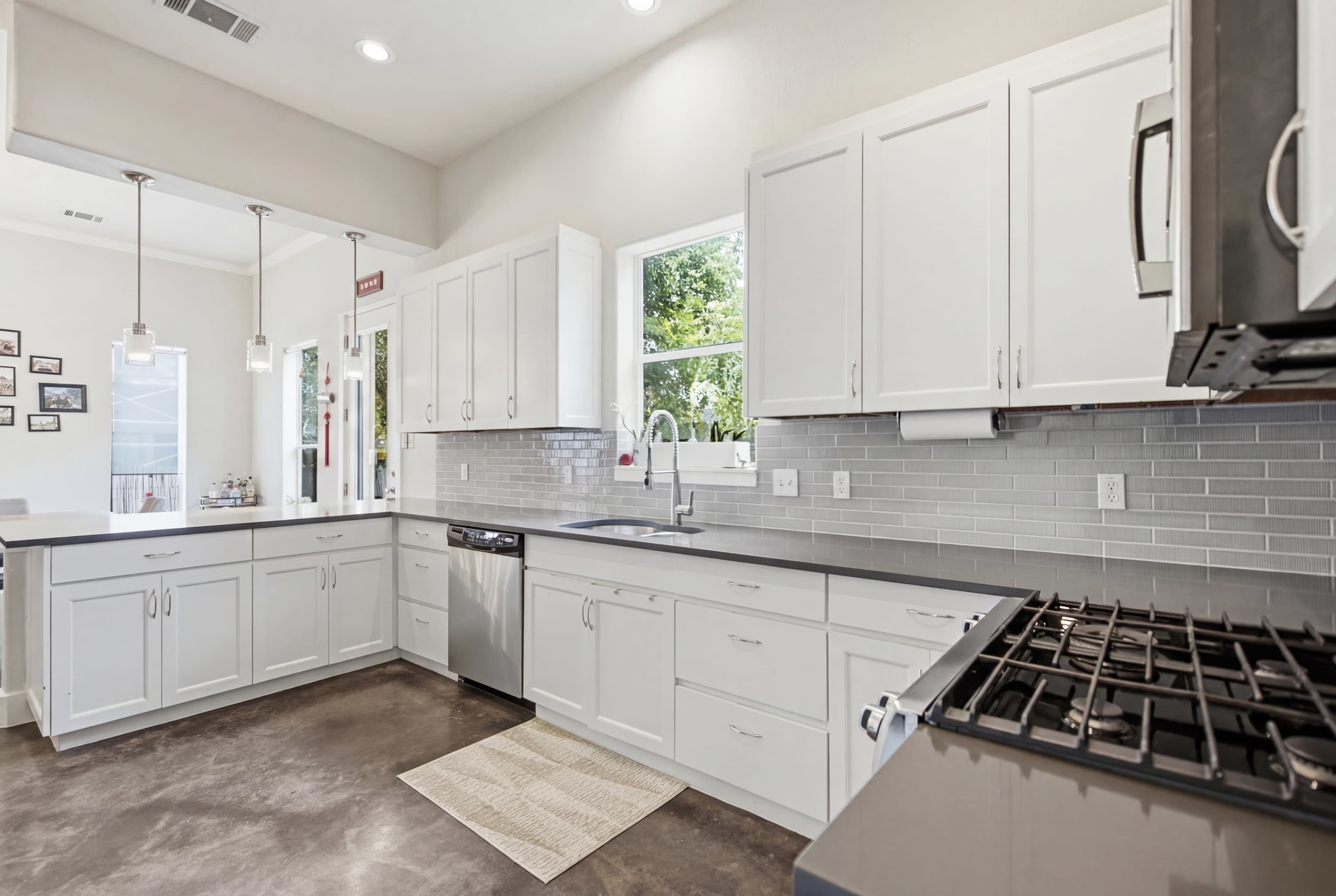 The image shows a modern kitchen featuring white cabinets, stainless steel appliances, and a granite countertop with an undermount sink.