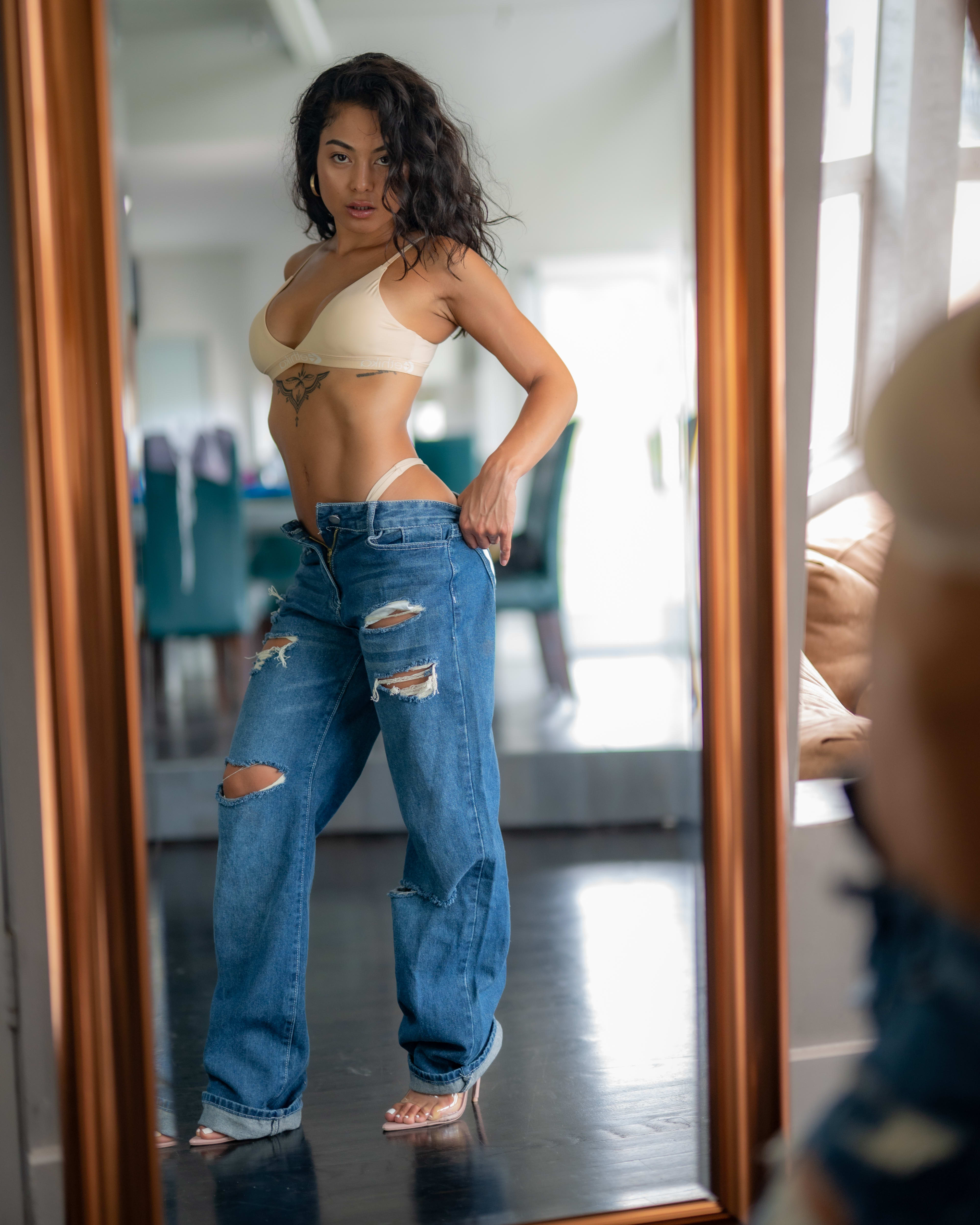 A woman posing for a fashion photoshoot in front of a mirror wearing beige clothing.