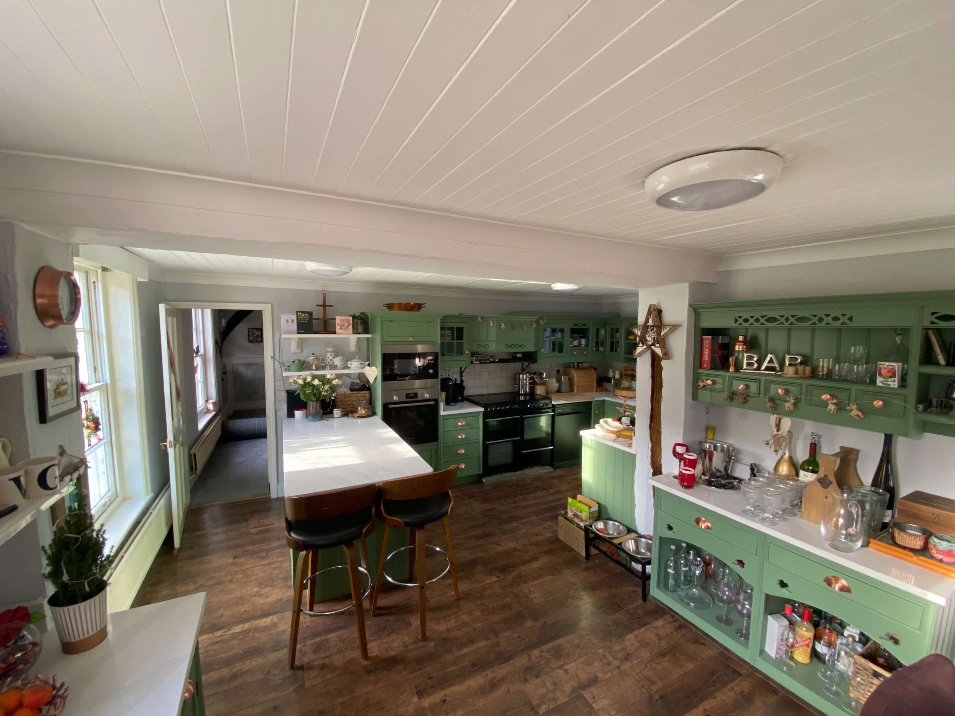 A bright, modern kitchen with teal cabinets, a central island with bar stools, and various kitchen appliances and decor.