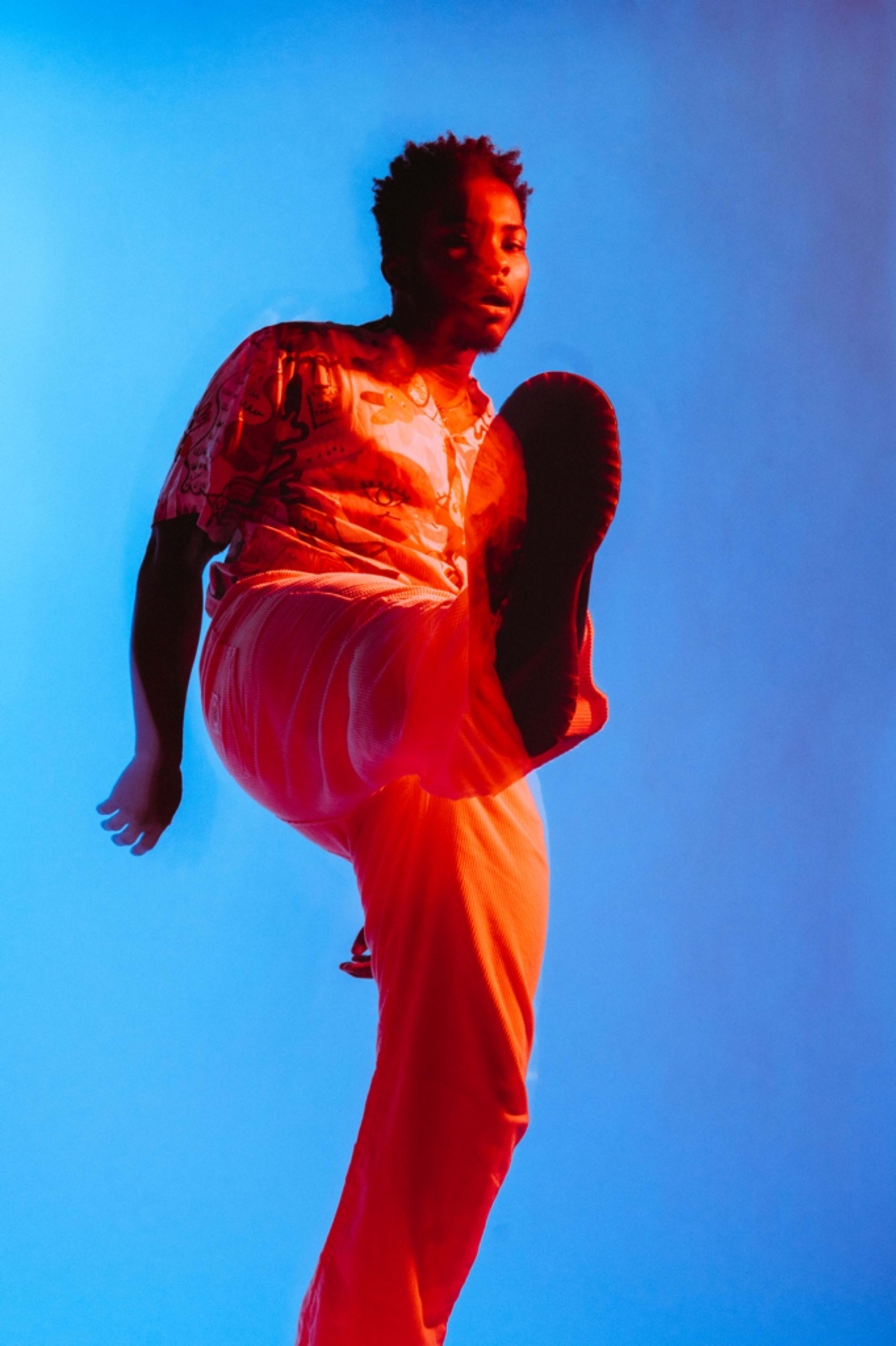 A person dressed in orange kicking during a photo shoot.