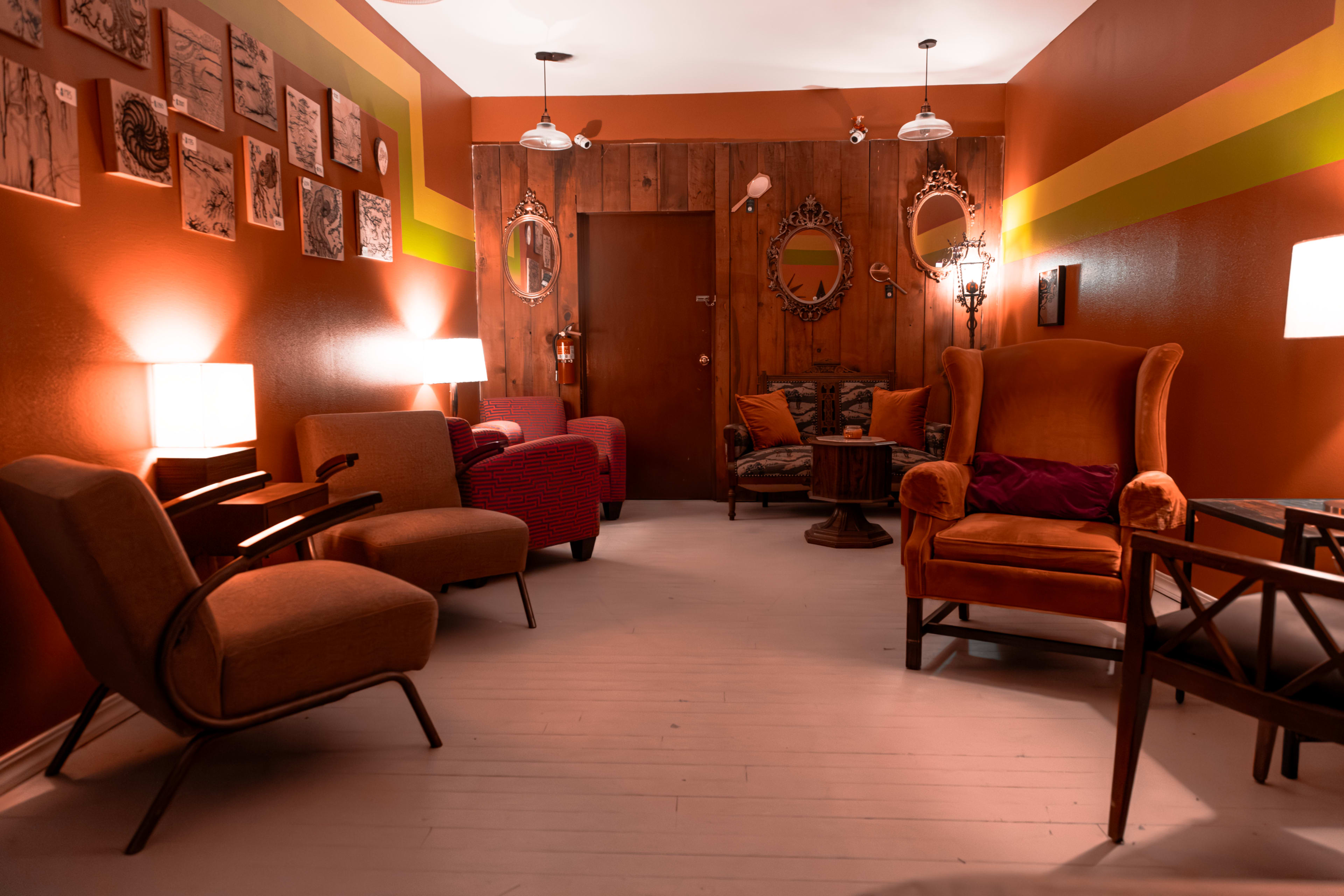 A cozy sitting area with several chairs and lamps, featuring warm, earthy tones and artistic wall decorations.