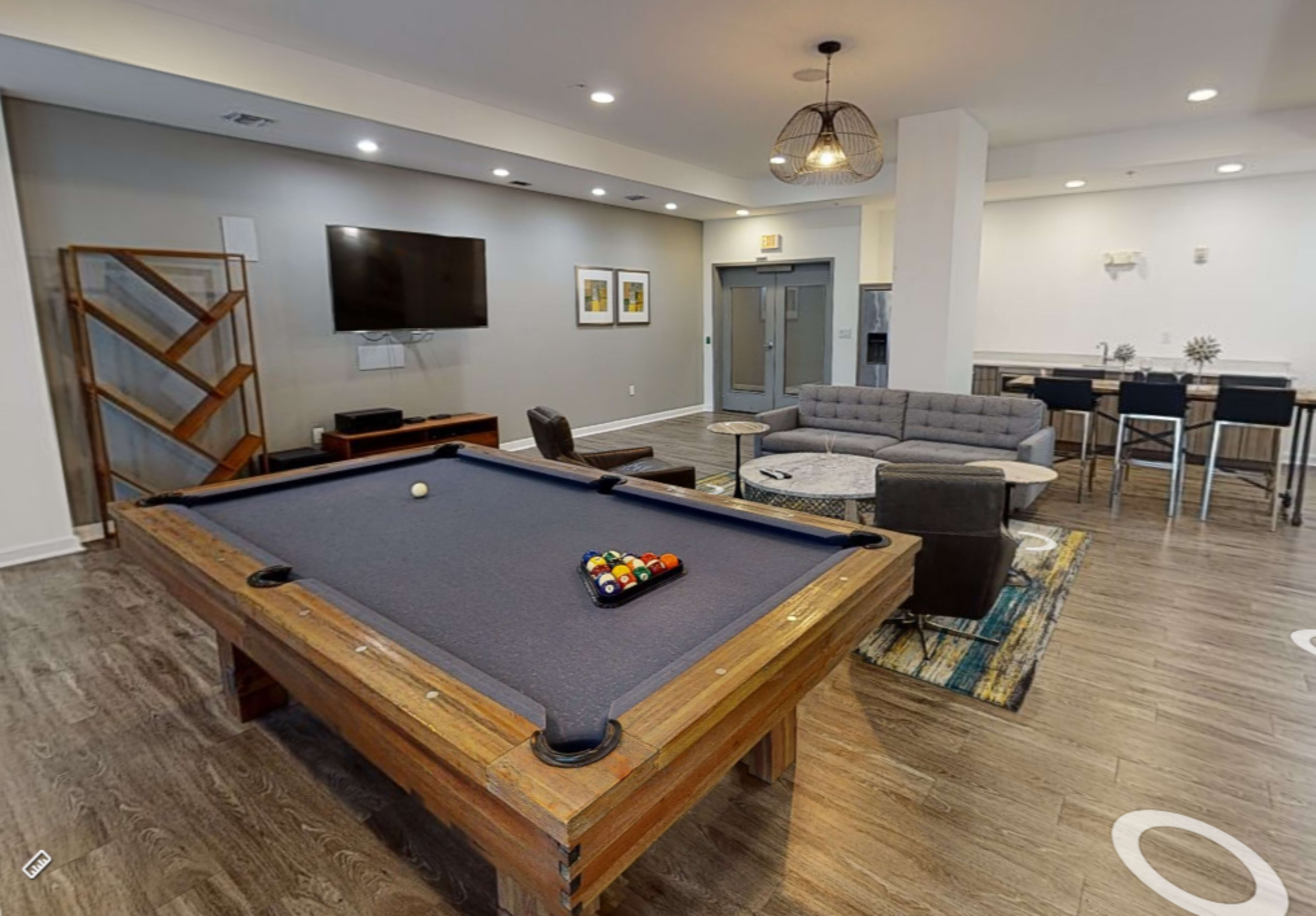 A game room featuring a pool table, a sofa area, a television, and a dining space with a small table and chairs.