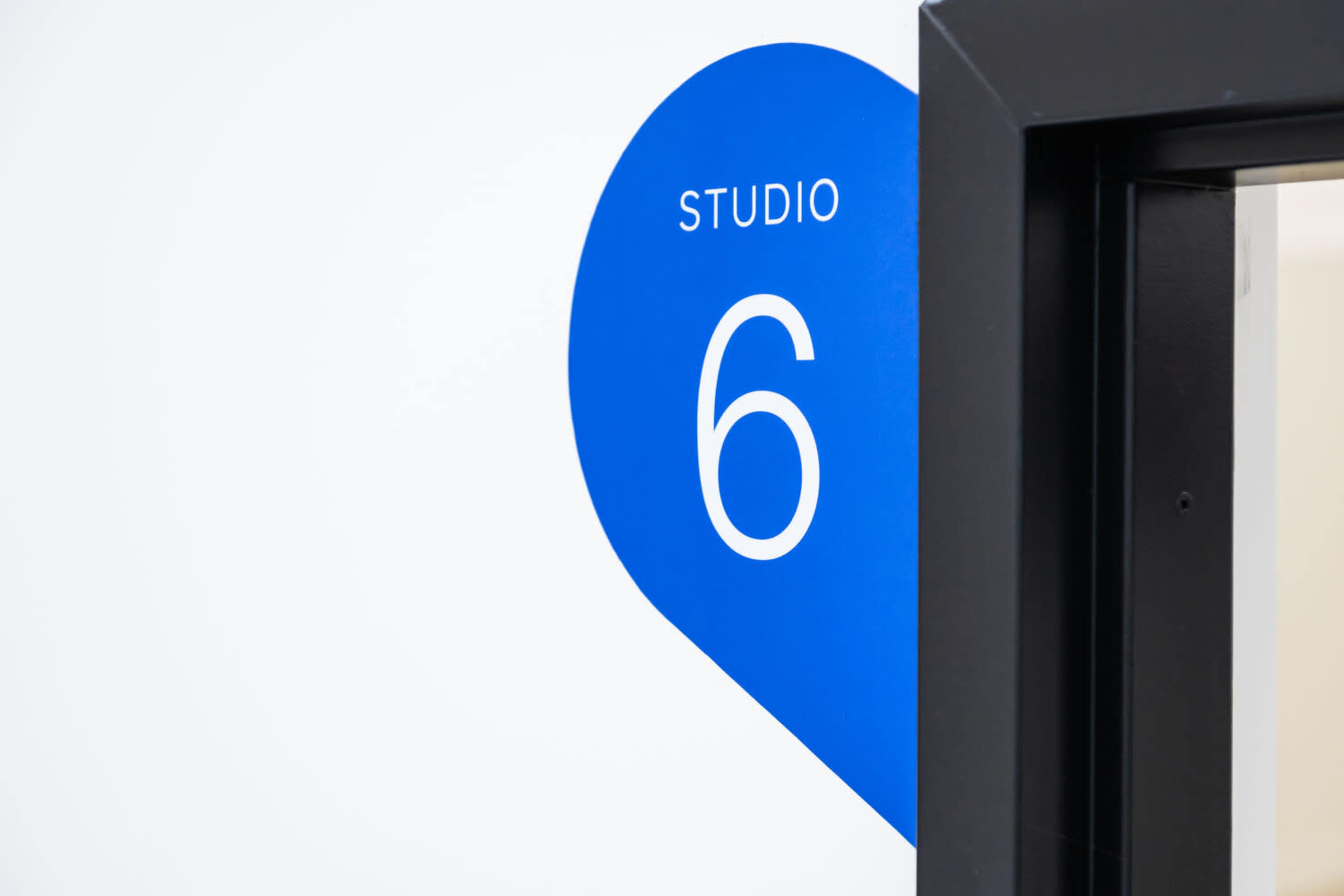 A blue sign labeled "STUDIO 6" is attached to a white wall next to a doorway.