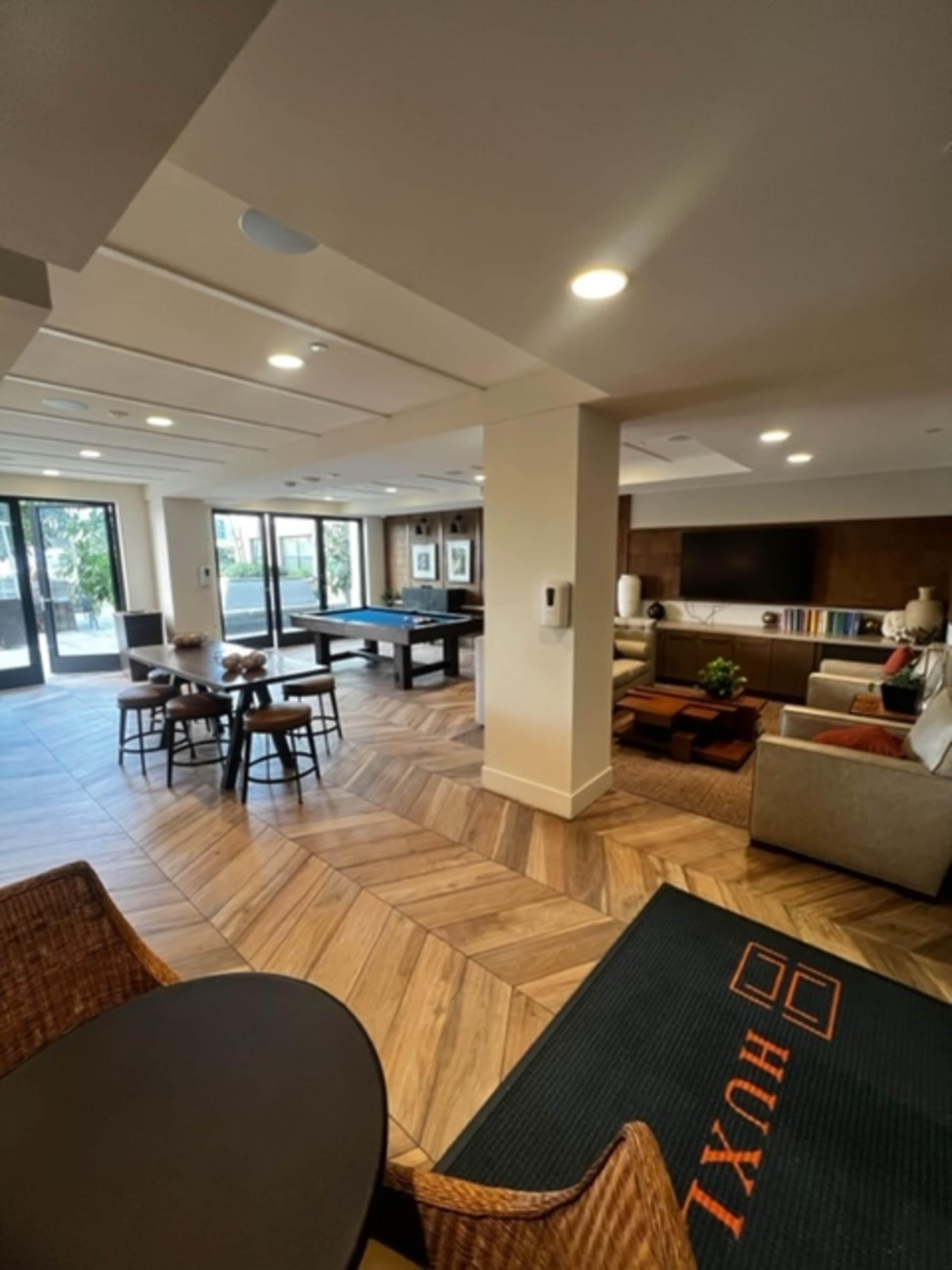 A spacious lounge area with a pool table, seating arrangements, and large windows letting in natural light.
