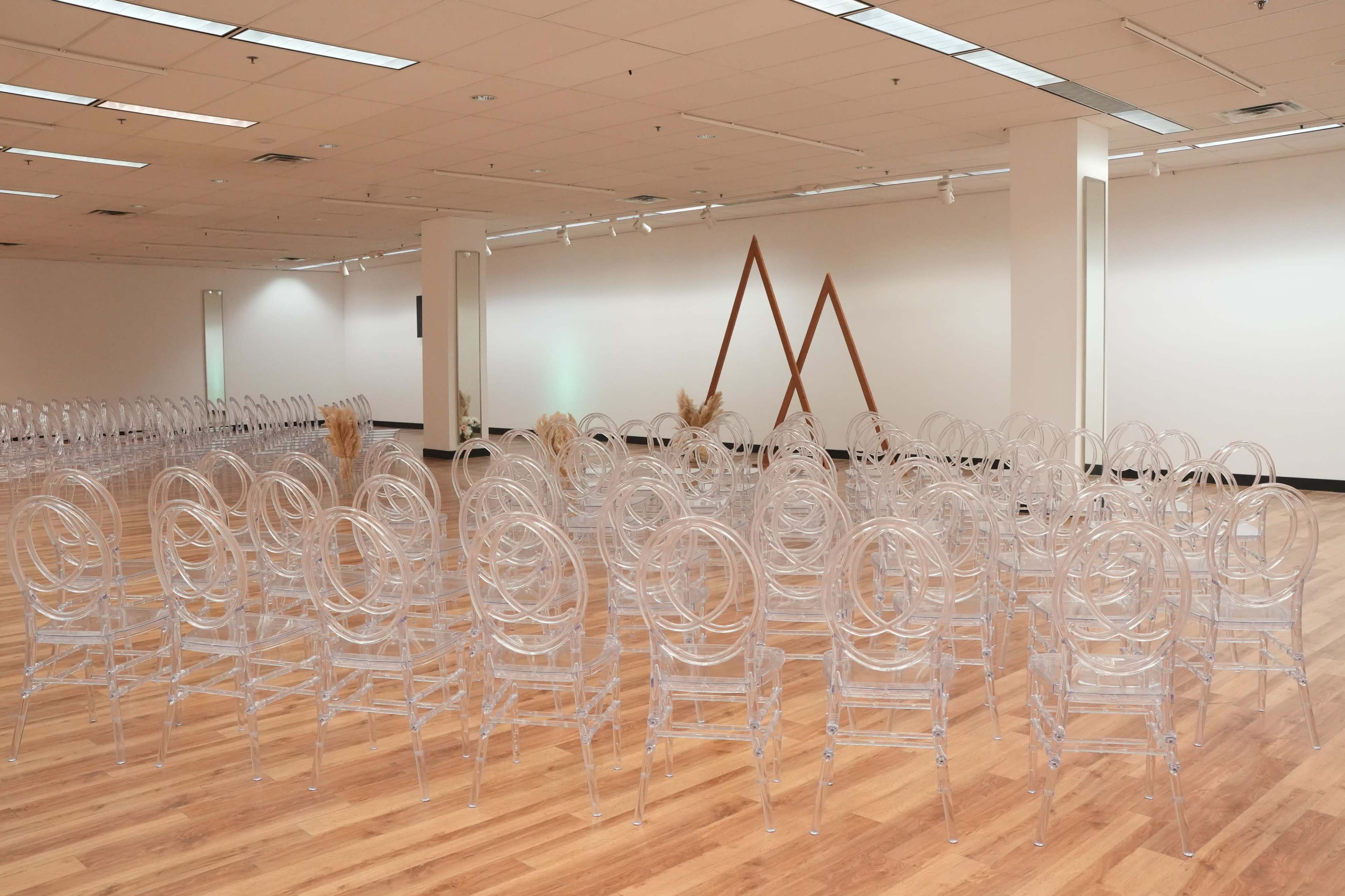A spacious room set up with multiple rows of transparent chairs arranged for an event.