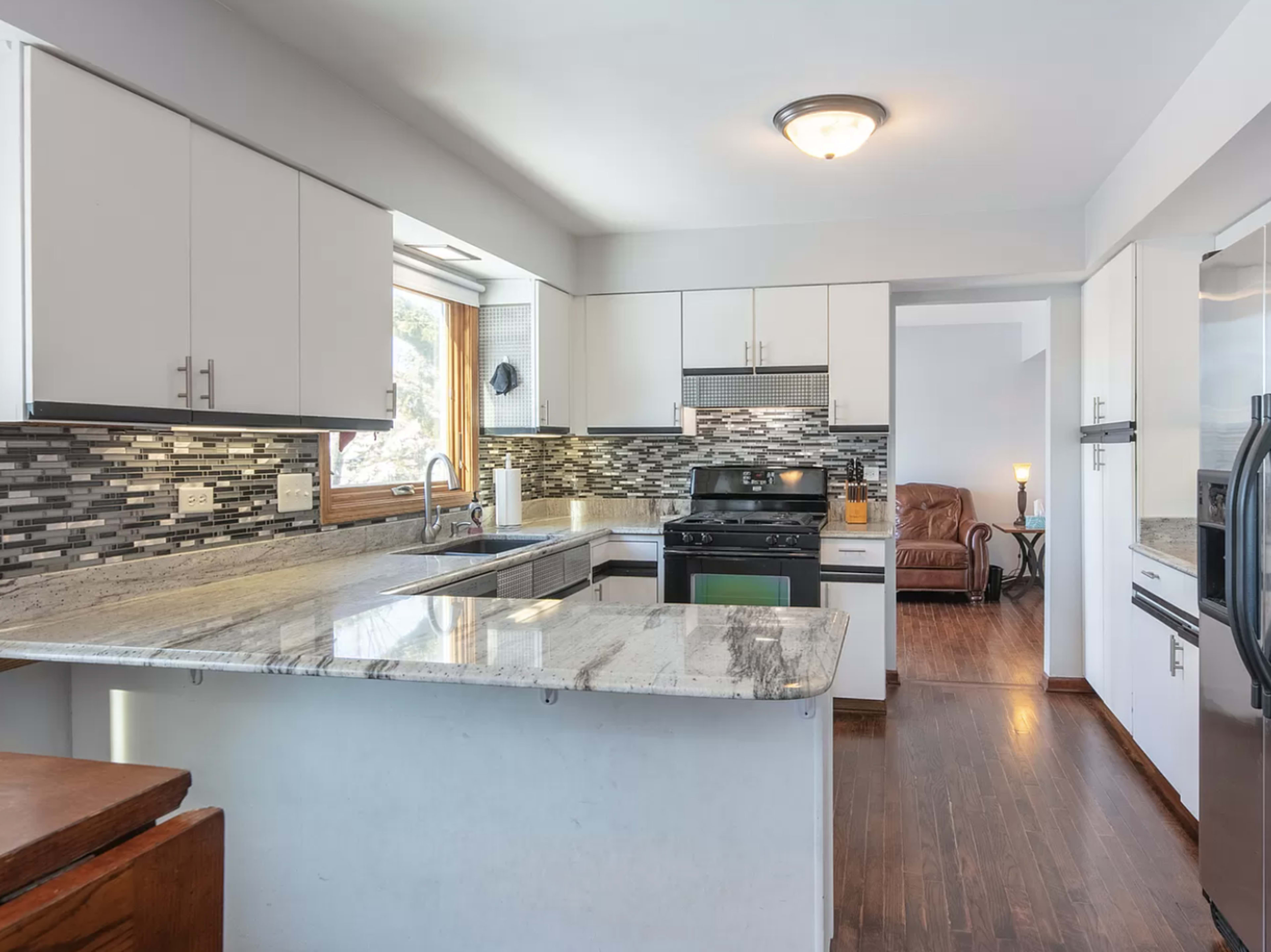 The image features a modern kitchen with granite countertops, stainless steel appliances, and a mosaic backsplash.