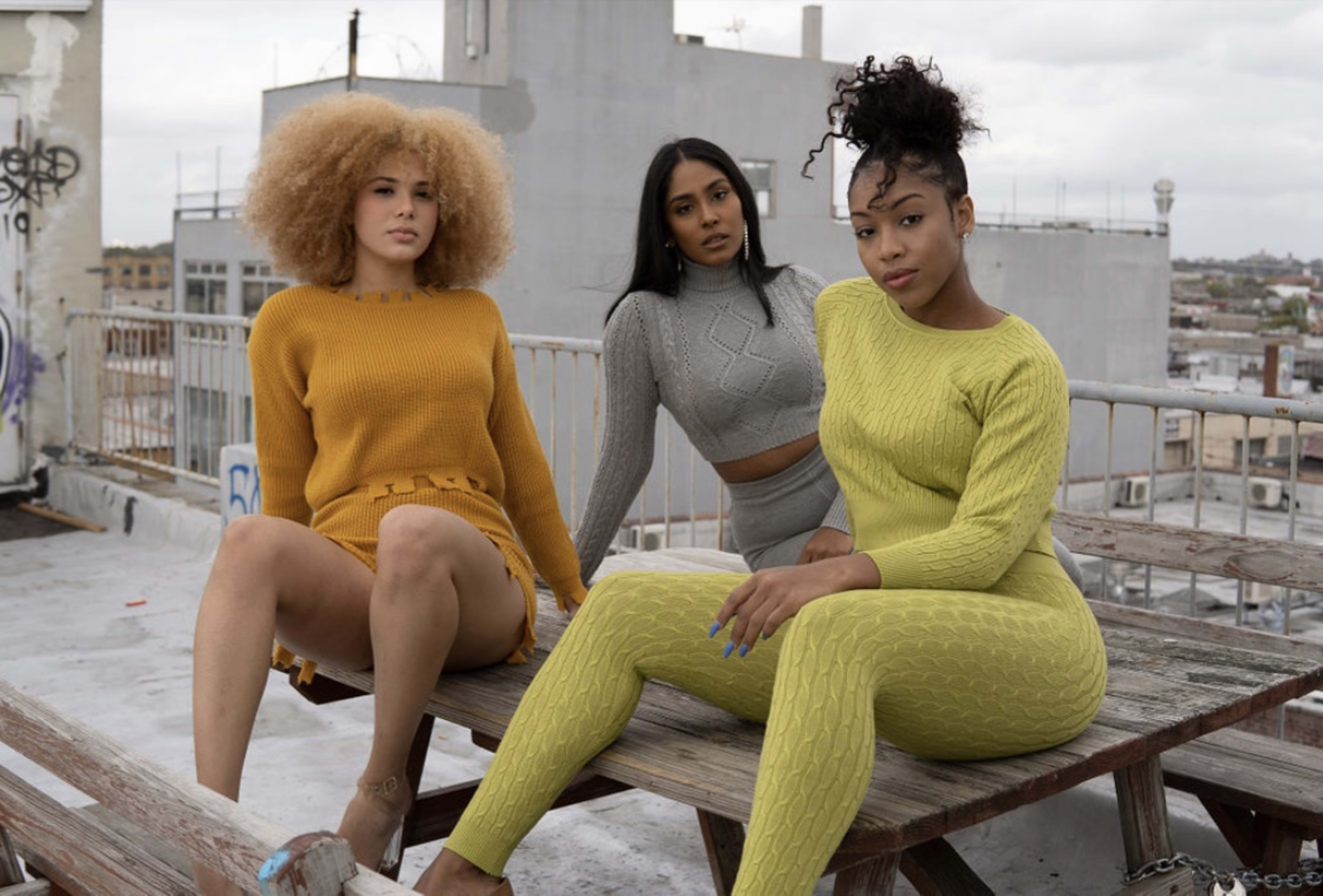 Three women having a photoshoot on a rustic rooftop bench.