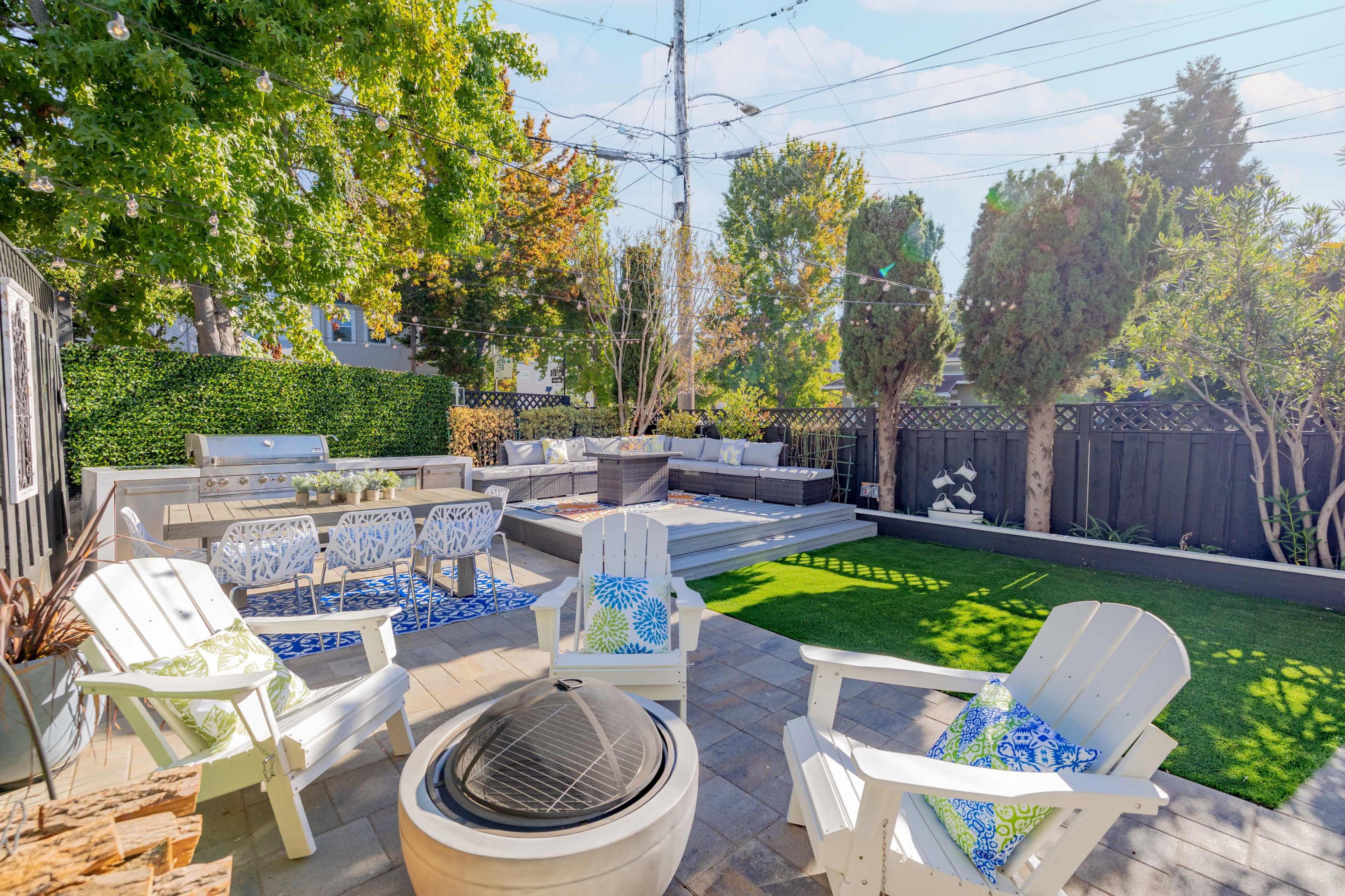 A backyard space with seating around a fire pit, a patio area with a barbecue, and landscaped greenery.