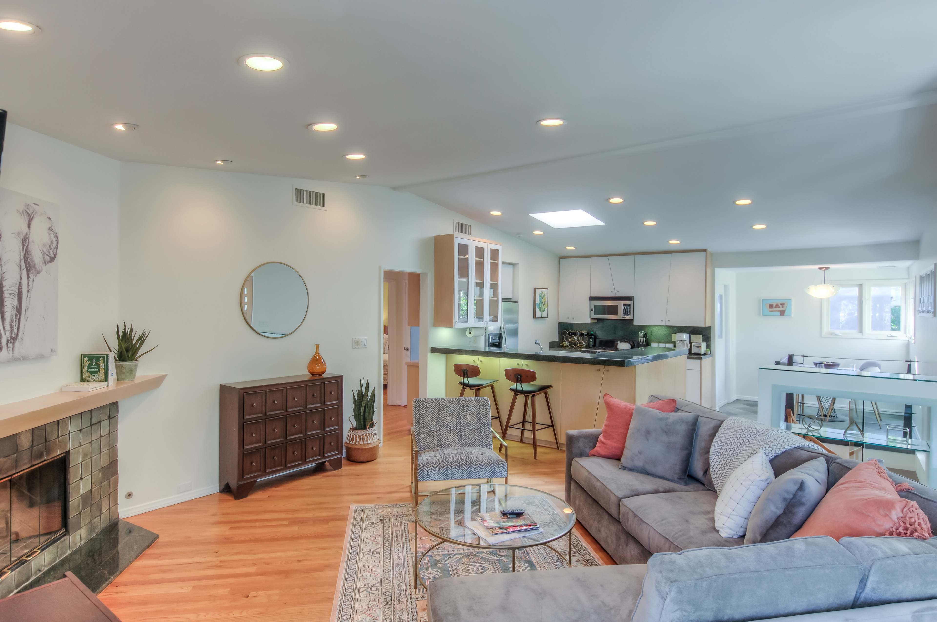 The image showcases a spacious living room with a modern design, featuring a comfortable sofa, a coffee table, and a fireplace, adjacent to a kitchen area with bar seating.