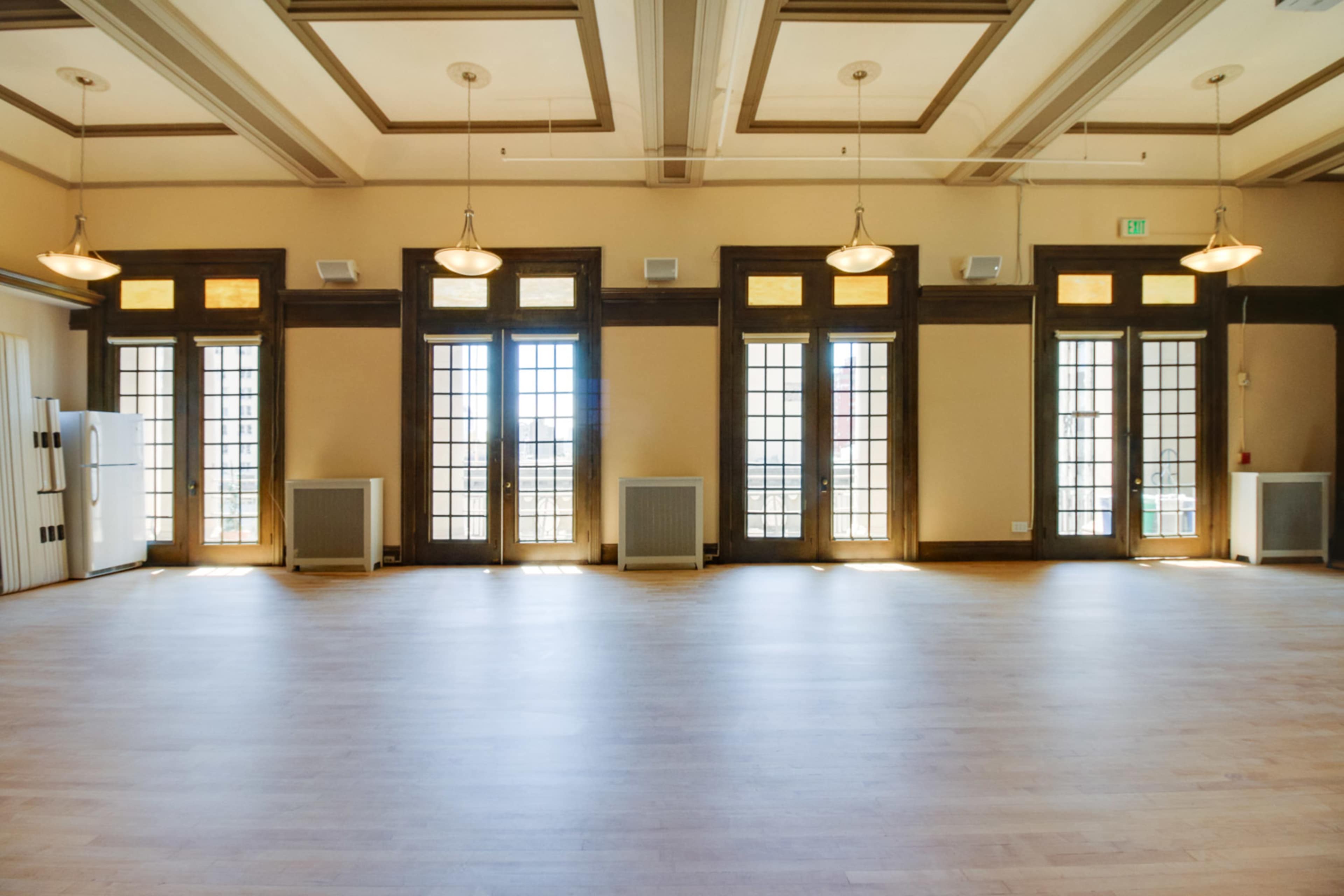 A spacious, well-lit indoor area with large windows and wooden ceiling beams.