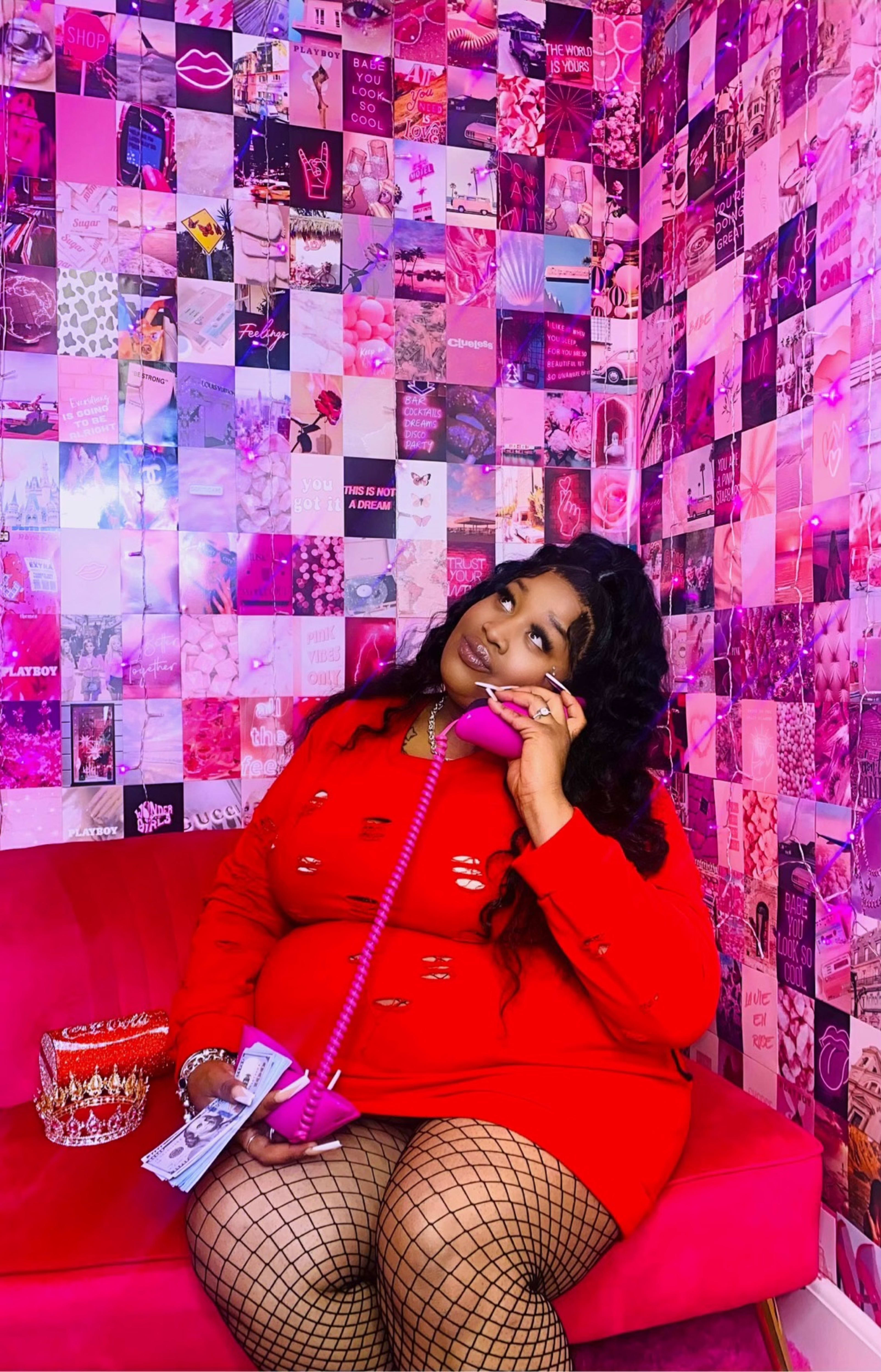 A woman talking on a phone while sitting on a pink couch.