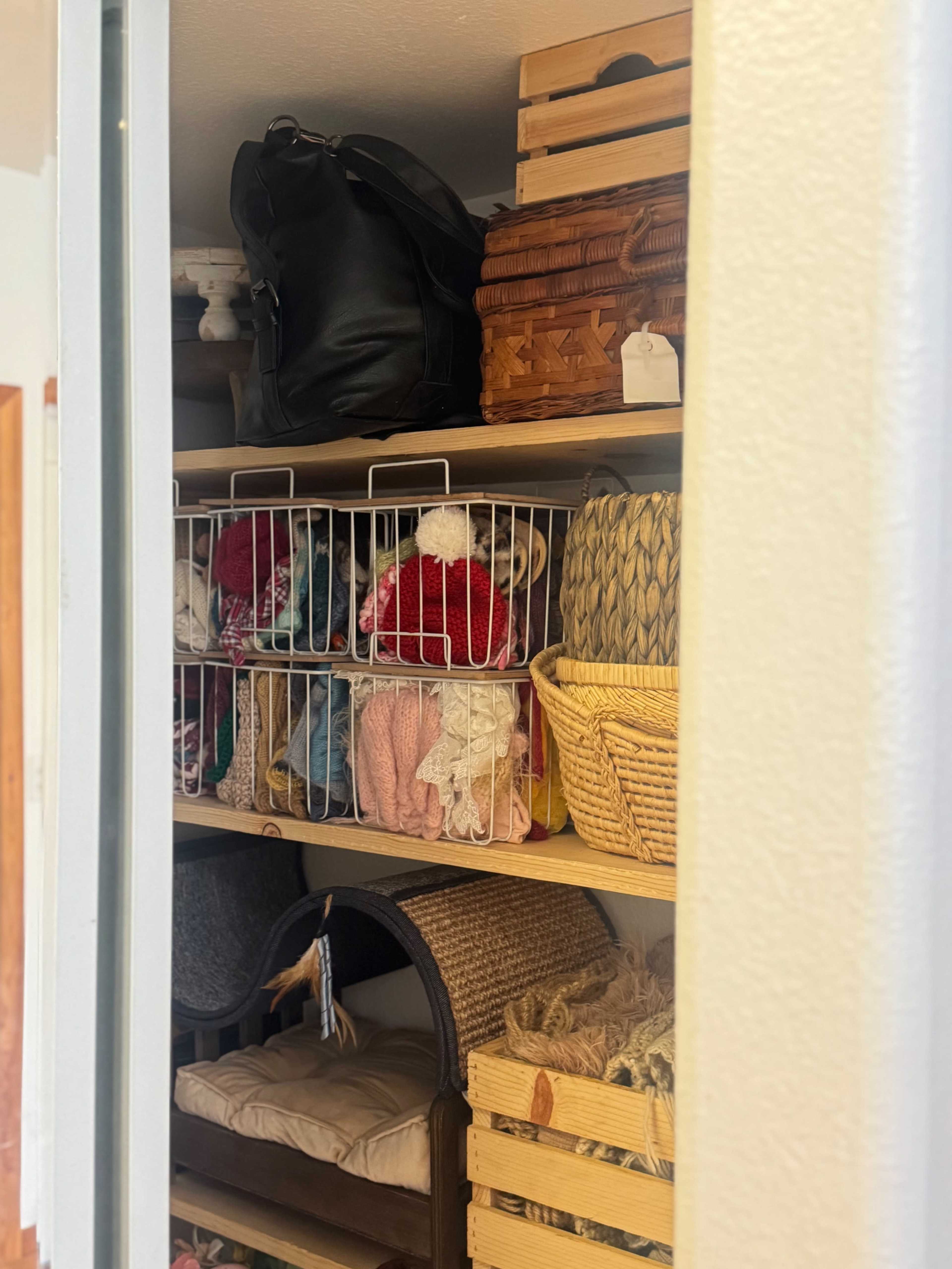The image shows a neatly organized closet with shelves filled with various baskets, fabric items, and storage containers.