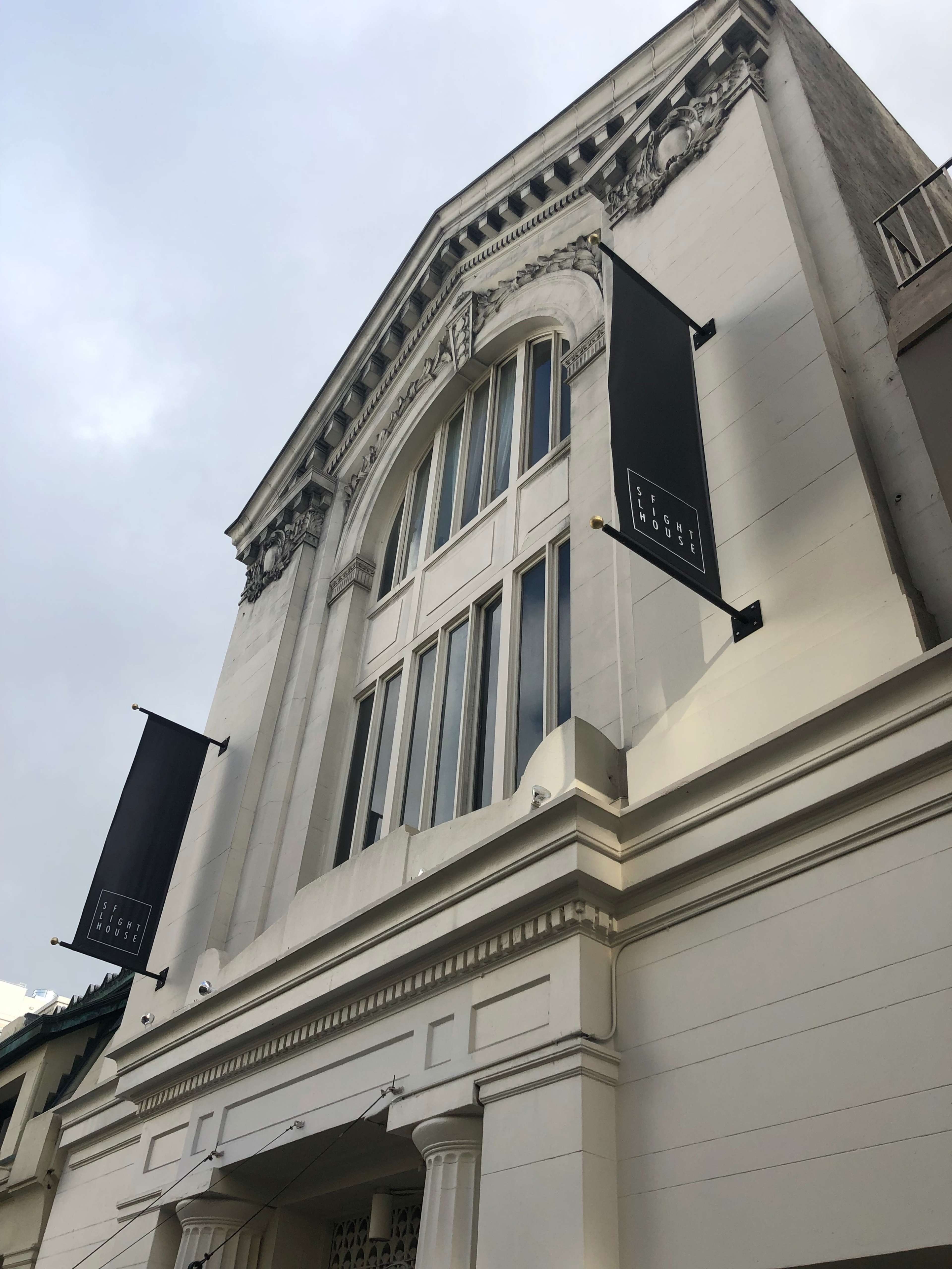 A historic building with a large arched window and two black banners hanging from it.
