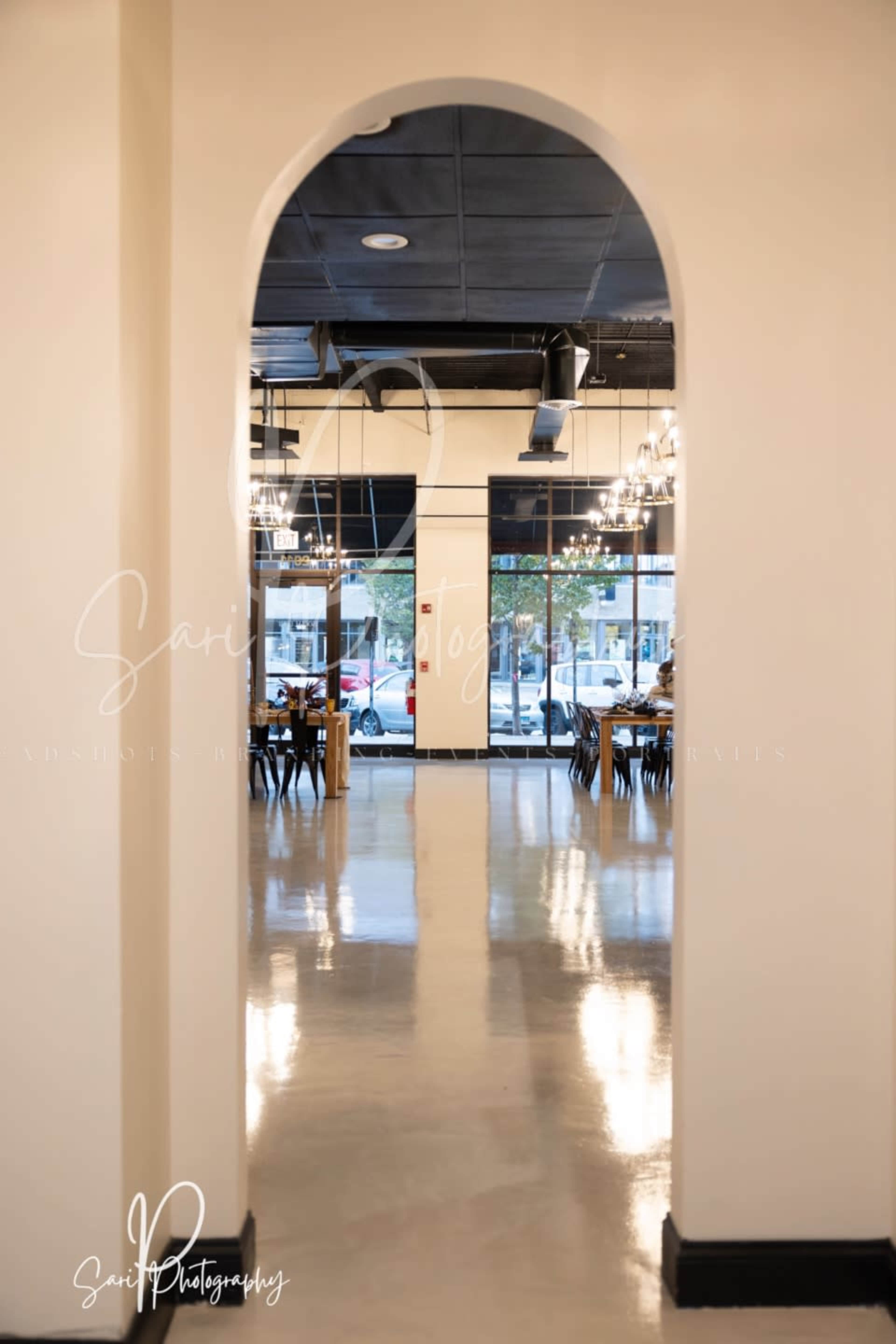 A hallway archway leading into a dining area of a restaurant with tables and chairs arranged neatly inside.