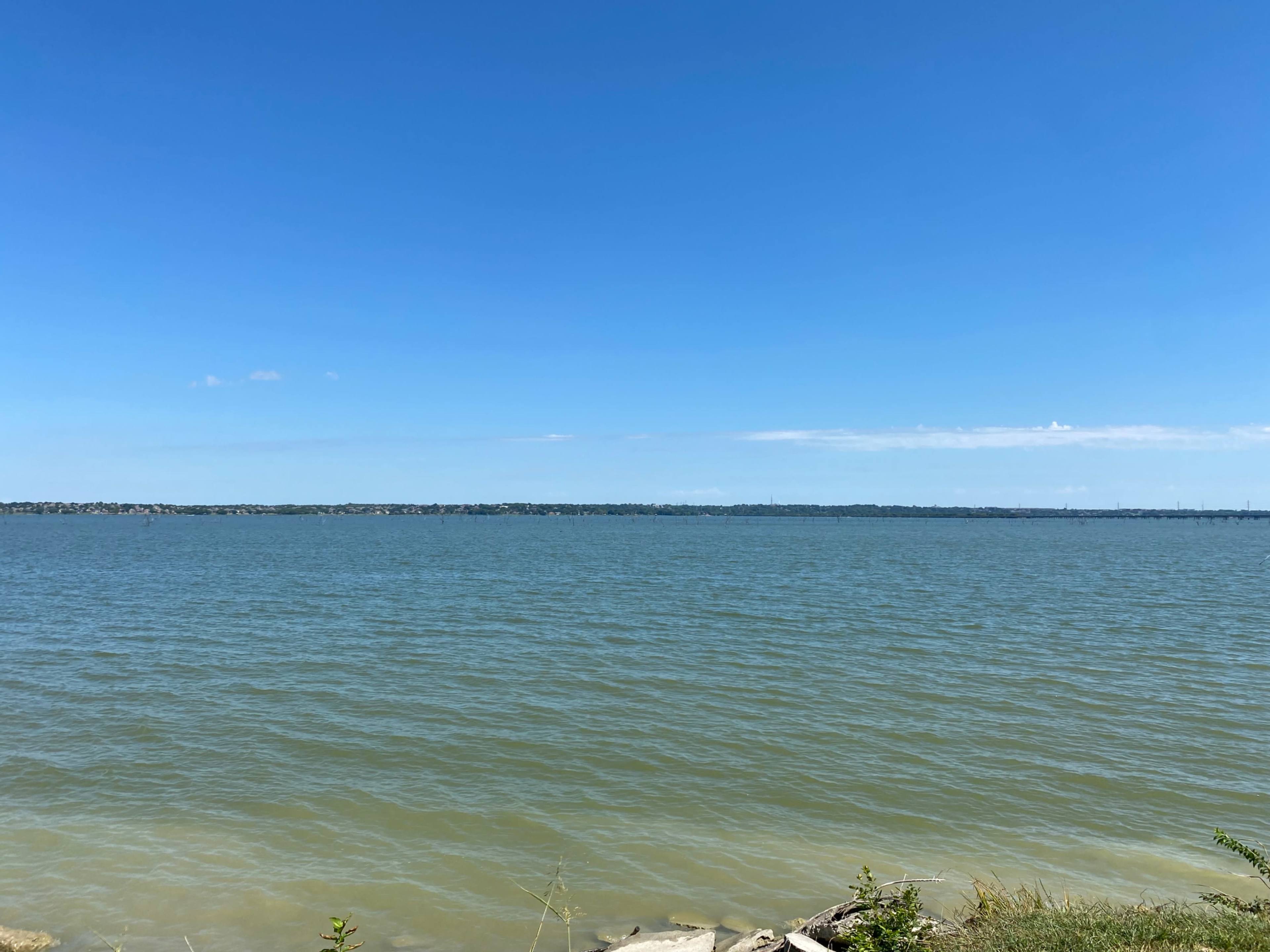 A calm lake stretches out under a clear blue sky.