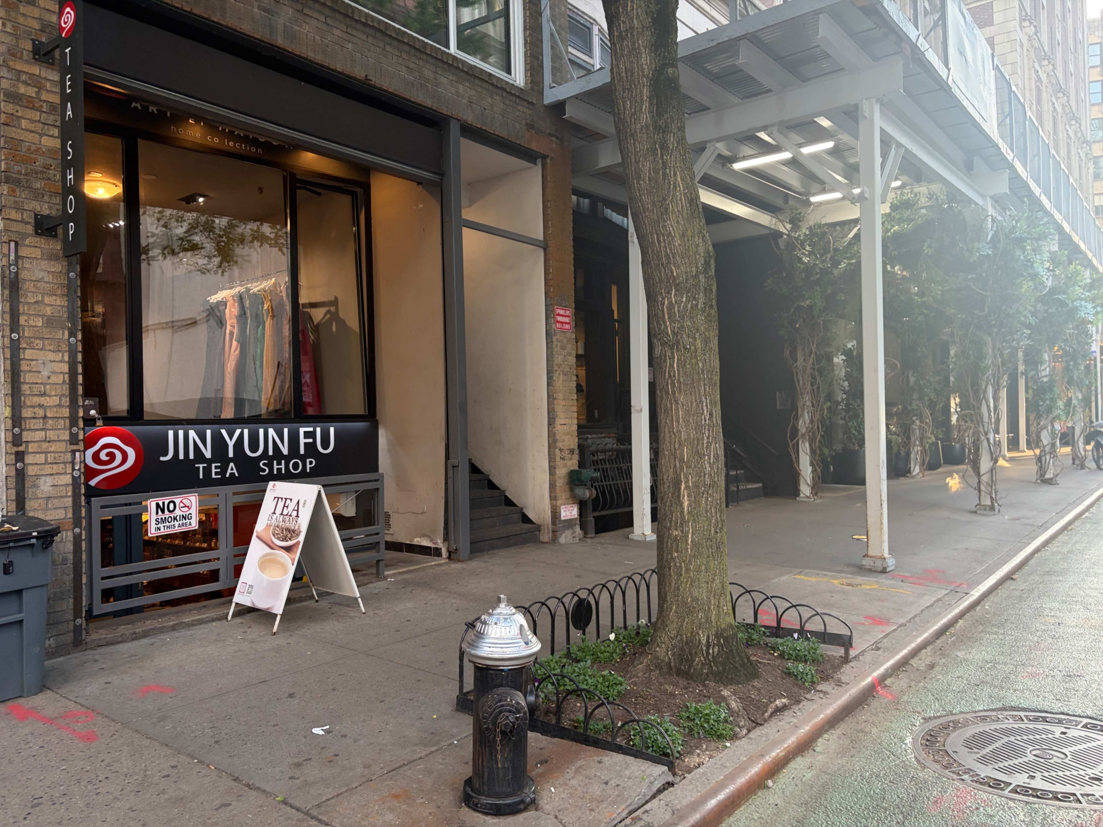 The image shows a street scene with a tea shop named "Jin Yun Fu Tea Shop" in a brick building, alongside a sidewalk with a fire hydrant and trees.