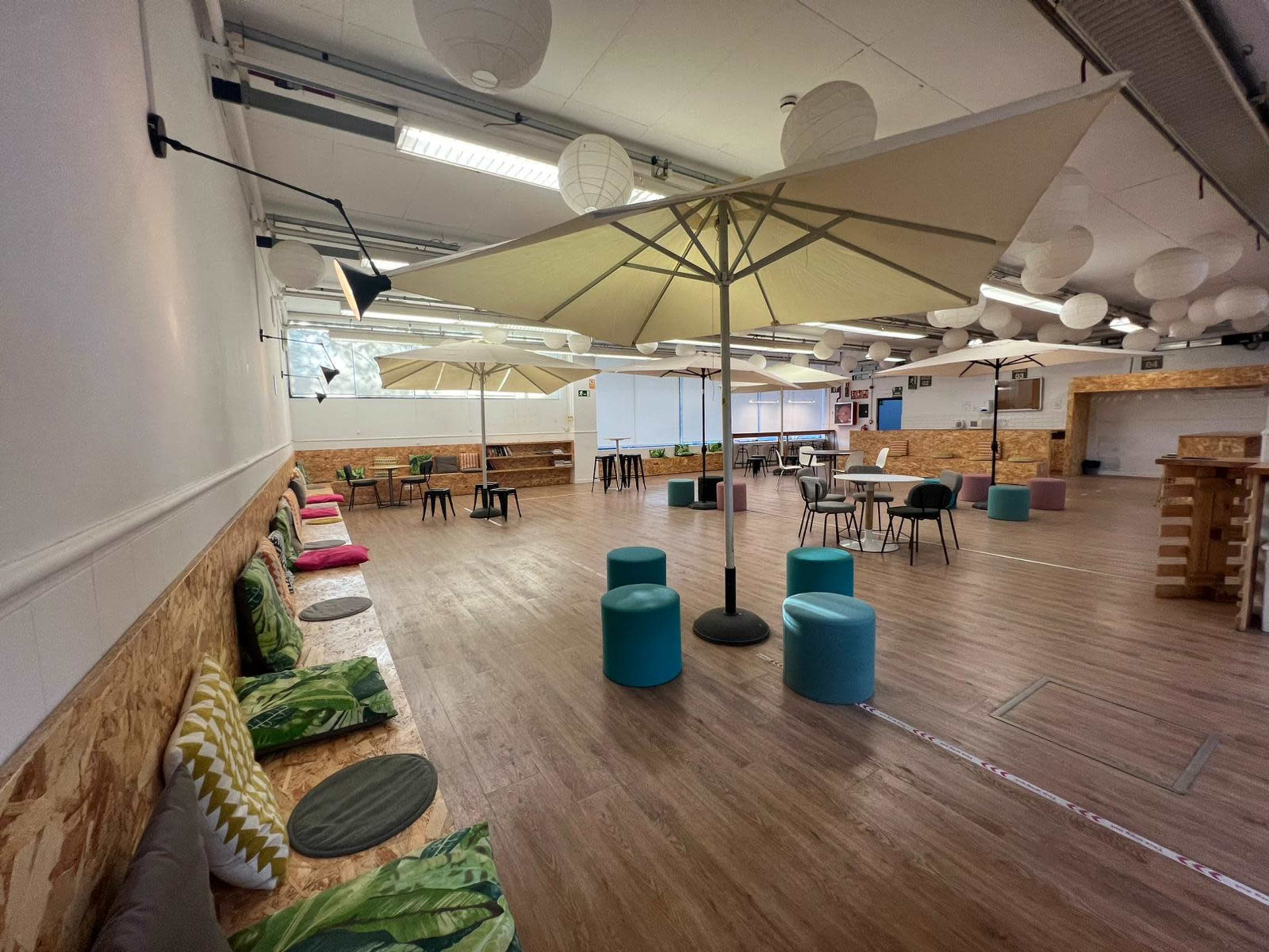 A spacious indoor area with seating arrangements, large umbrellas, and wooden decor.