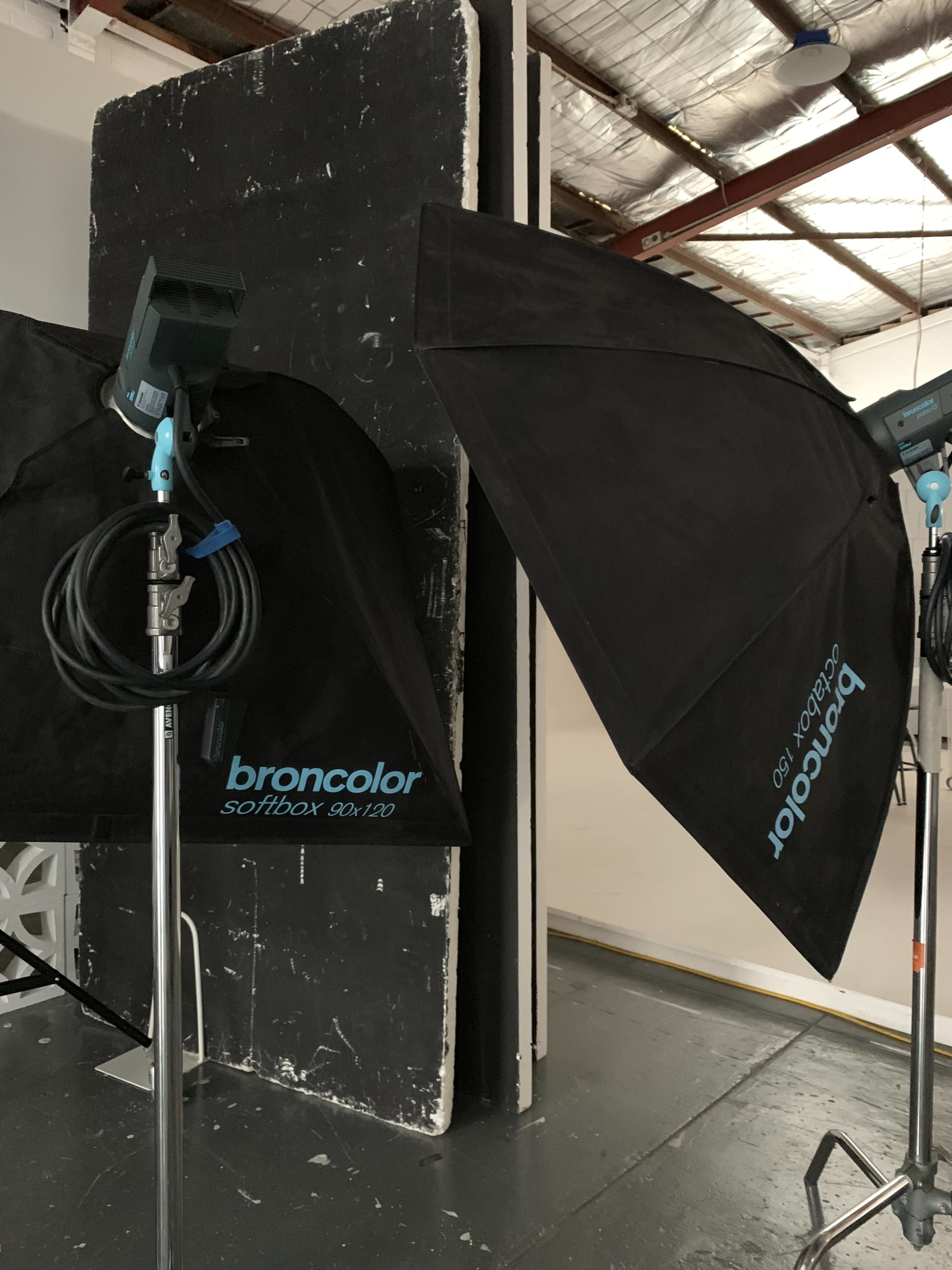 The image shows two Broncolor softboxes positioned on stands, facing a textured backdrop in a photography studio.
