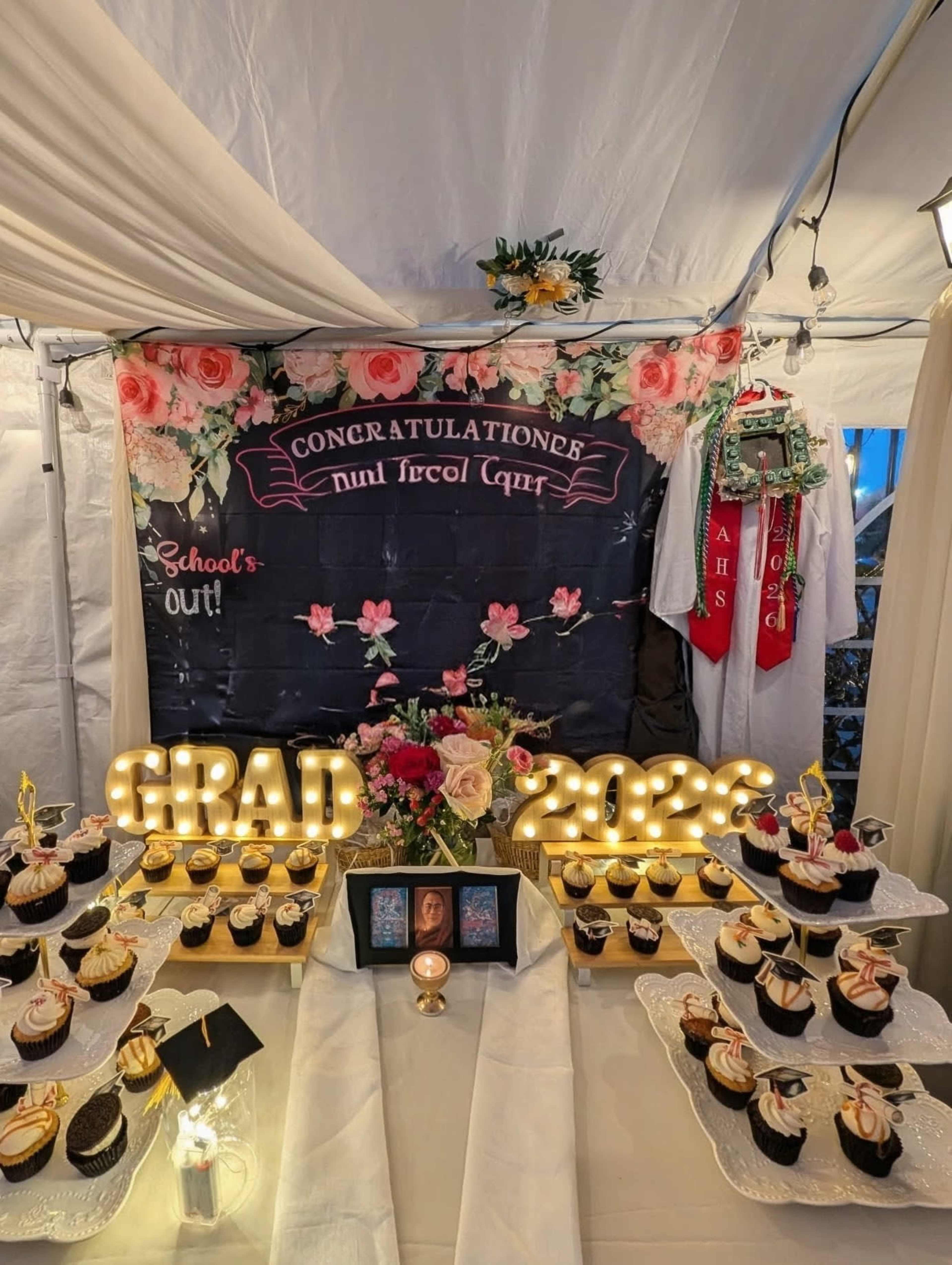 The image shows a decorated table with cupcakes and a backdrop celebrating graduation, featuring the text "CONGRATULATIONS" and "SCHOOL'S OUT!" along with light-up numbers reading "2023".