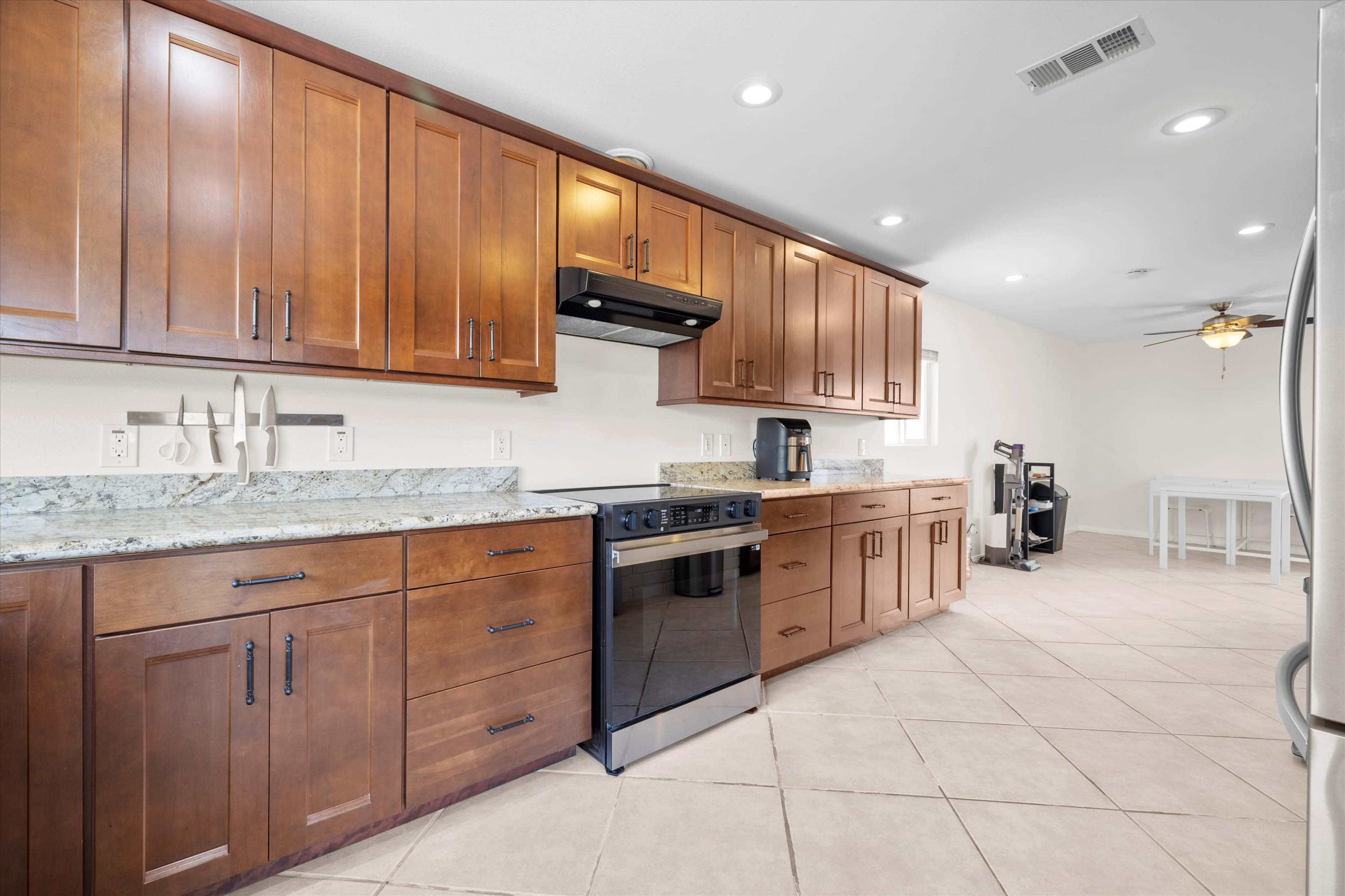 The image shows a modern kitchen with wooden cabinets, a stainless steel stove, and countertops made of granite.